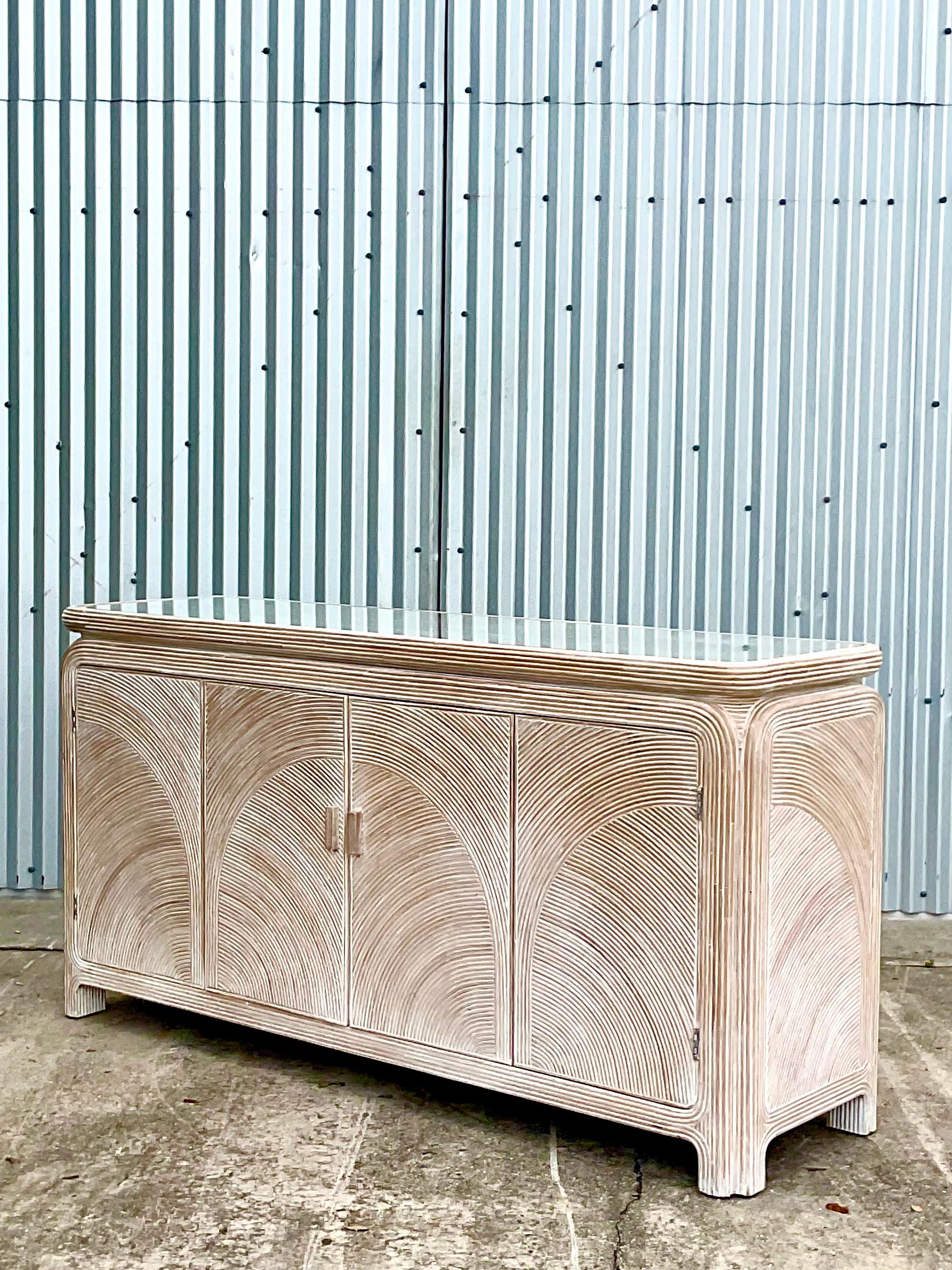 Fantastic vintage pencil reed credenza. Beautiful swirl design in the reed. Inset glass top. Acquired from a Palm Beach estate.