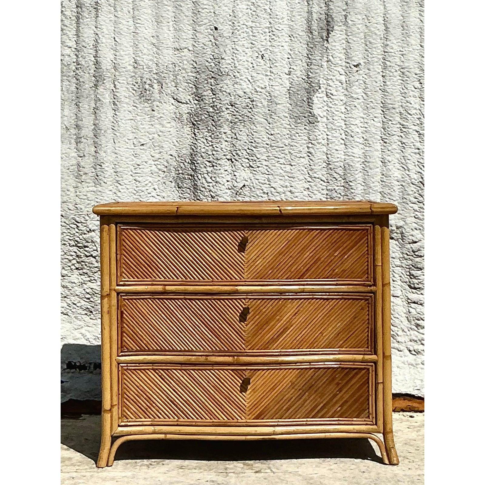 Bring the serene charm of coastal living into your home with this vintage pencil reed chest of drawers, crafted in an elegant chevron pattern. Wrapped in hand-applied rattan and framed with bamboo trim, this piece radiates natural warmth and organic