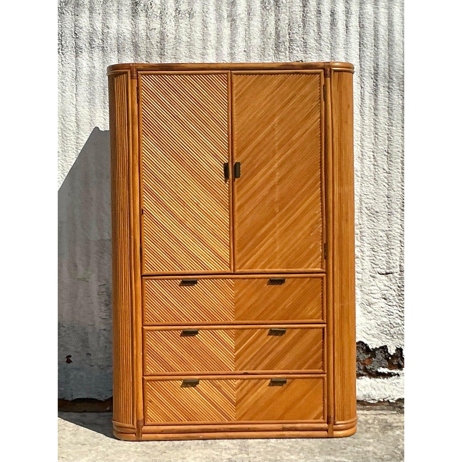 Elevate your interior with this stunning vintage coastal armoire, crafted from natural reed in a striking chevron pattern. The finely woven design creates a dynamic visual texture, beautifully complemented by the rounded edges and warm honey-toned