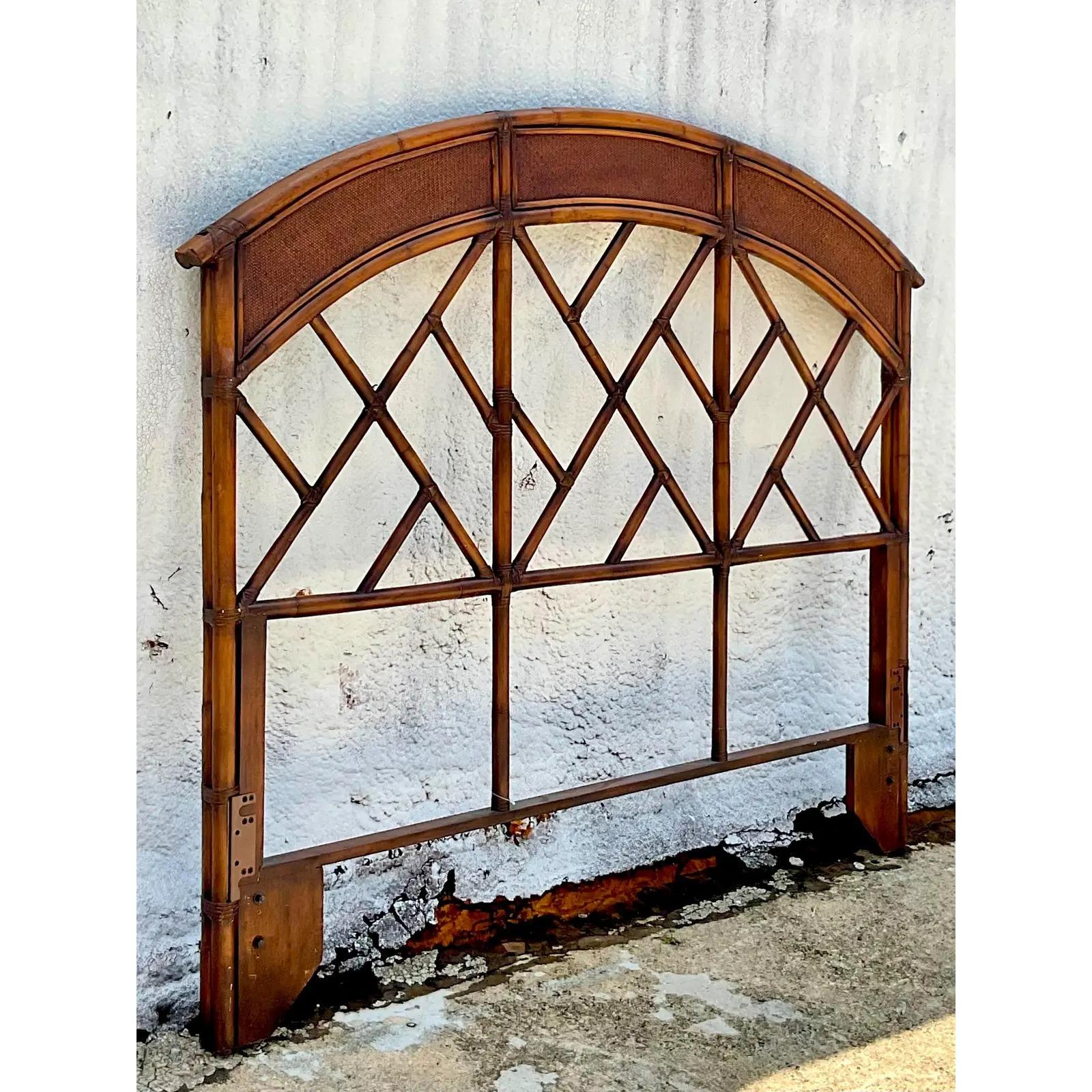 Fantastic vintage Queen headboard. Beautiful arched design with the coveted Chinese Chippendale motif. Inset woven rattan panels. Acquired from a Palm Beach estate.