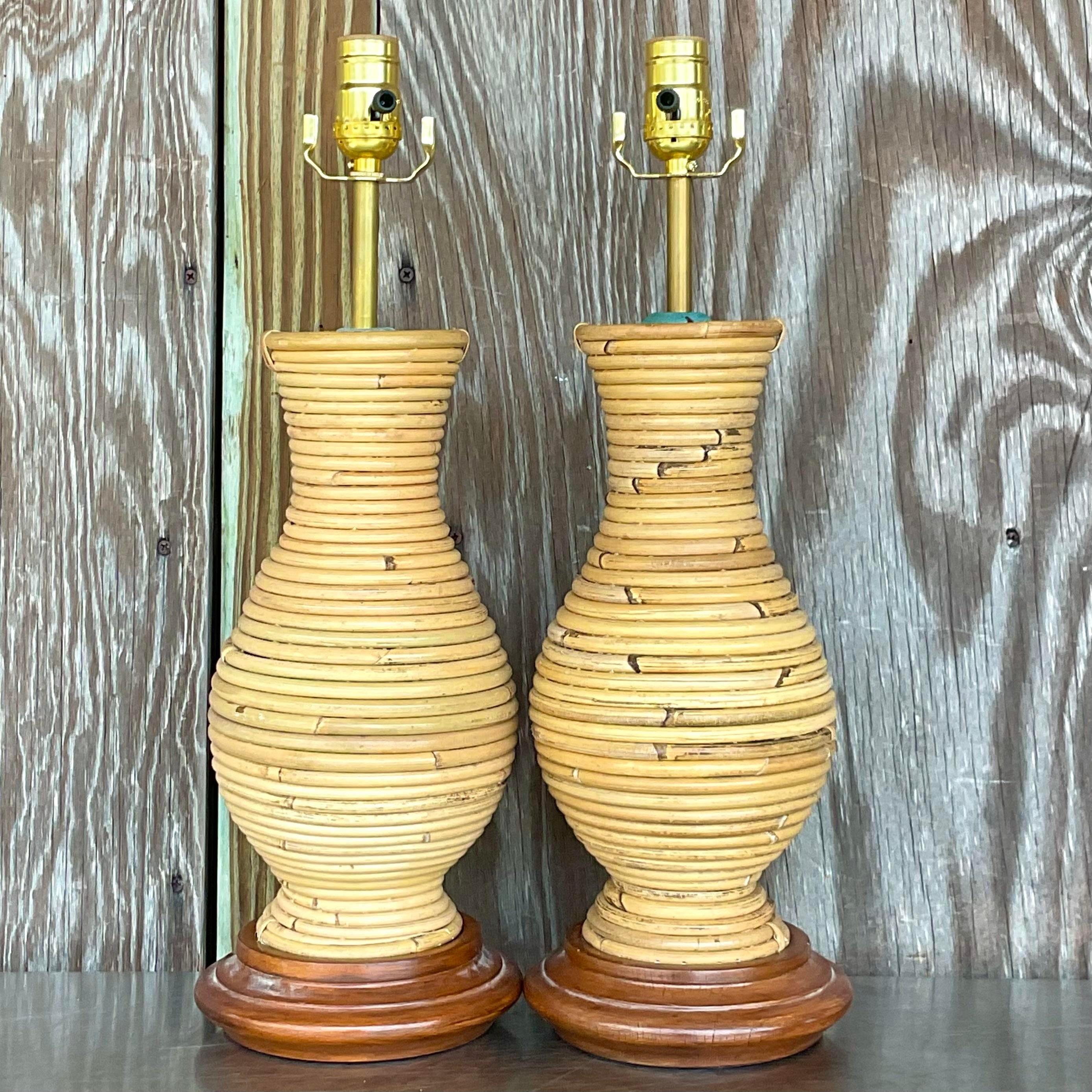 A stunning pair of vintage Coastal table lamps. Chic coiled pencil reed on a wooden plinth. Patinated metal hardware on top. Fully restored with all new wiring and hardware. Acquired from a Palm Beach estate.