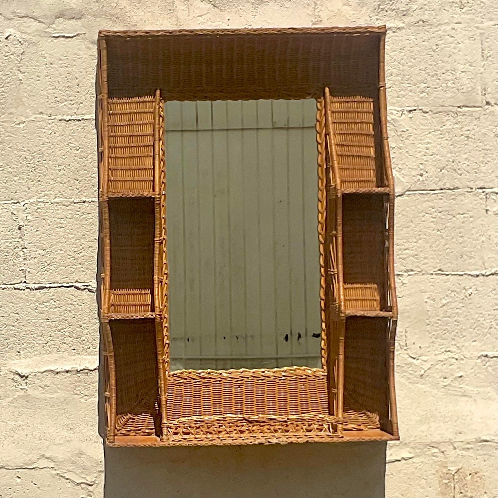 A stunning vintage Coastal wall mirror. A chic woven rattan with a series of built in shelves. Perfect for your small collections or even just a catch all for your keys. You decide! Acquired from a Palm Beach estate. 