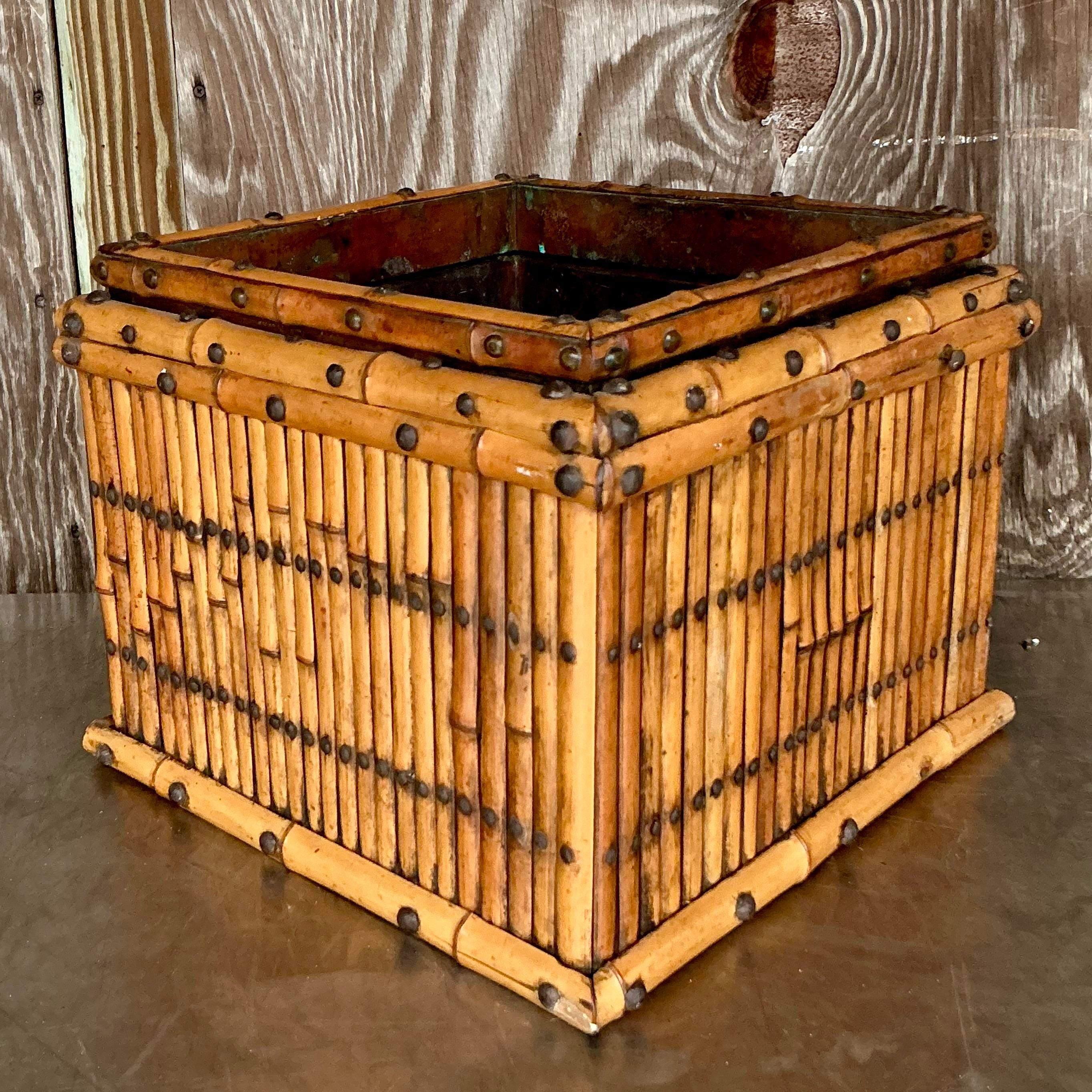 Bringen Sie eine Küstenatmosphäre in Ihr Zuhause mit diesem Vintage-Bambus-Pflanzgefäß, das mit Kupfer ausgekleidet ist und einen Hauch von Eleganz versprüht. Die natürliche Bambusstruktur kontrastiert wunderschön mit dem warmen Metallglanz, wodurch