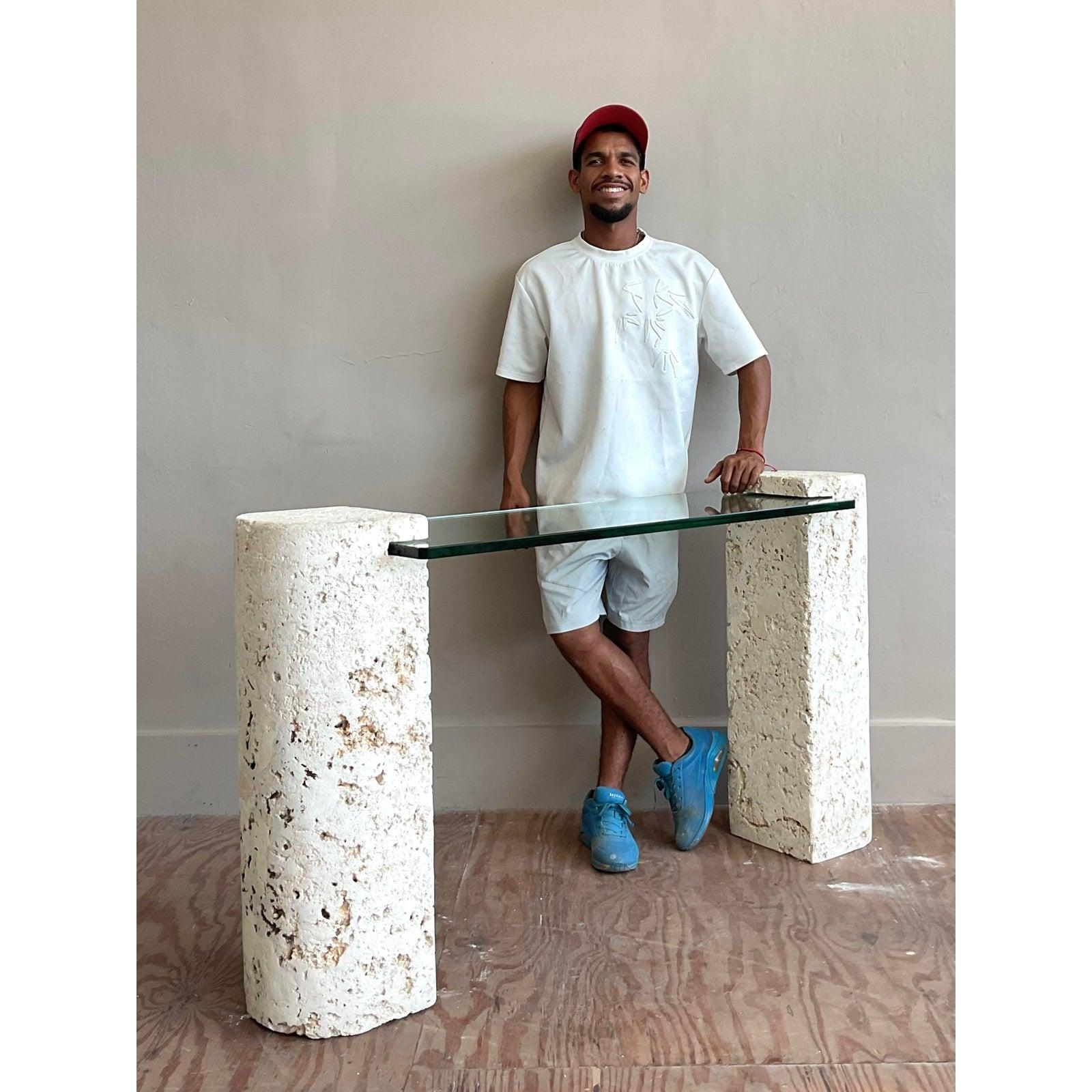 A stunning example of 1980s postmodern design, this captivating console table makes a bold architectural statement. The piece features two monumental pedestal bases crafted from genuine coquina stone, a unique material prized for its highly-textured