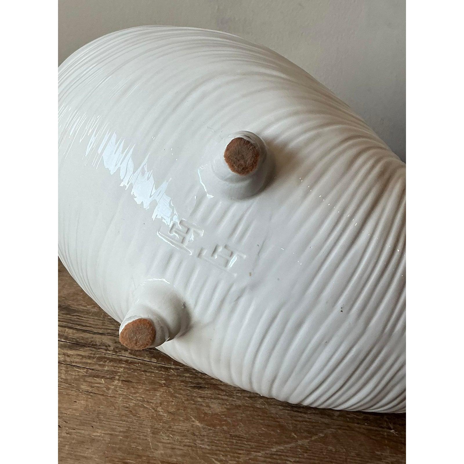 Questo affascinante cachepot vintage in ceramica è modellato e smaltato meticolosamente a forma di conchiglia di nautilus, incarnando la sofisticata estetica nautica e costiera della metà e della fine del XX secolo. Il pezzo è caratterizzato da un