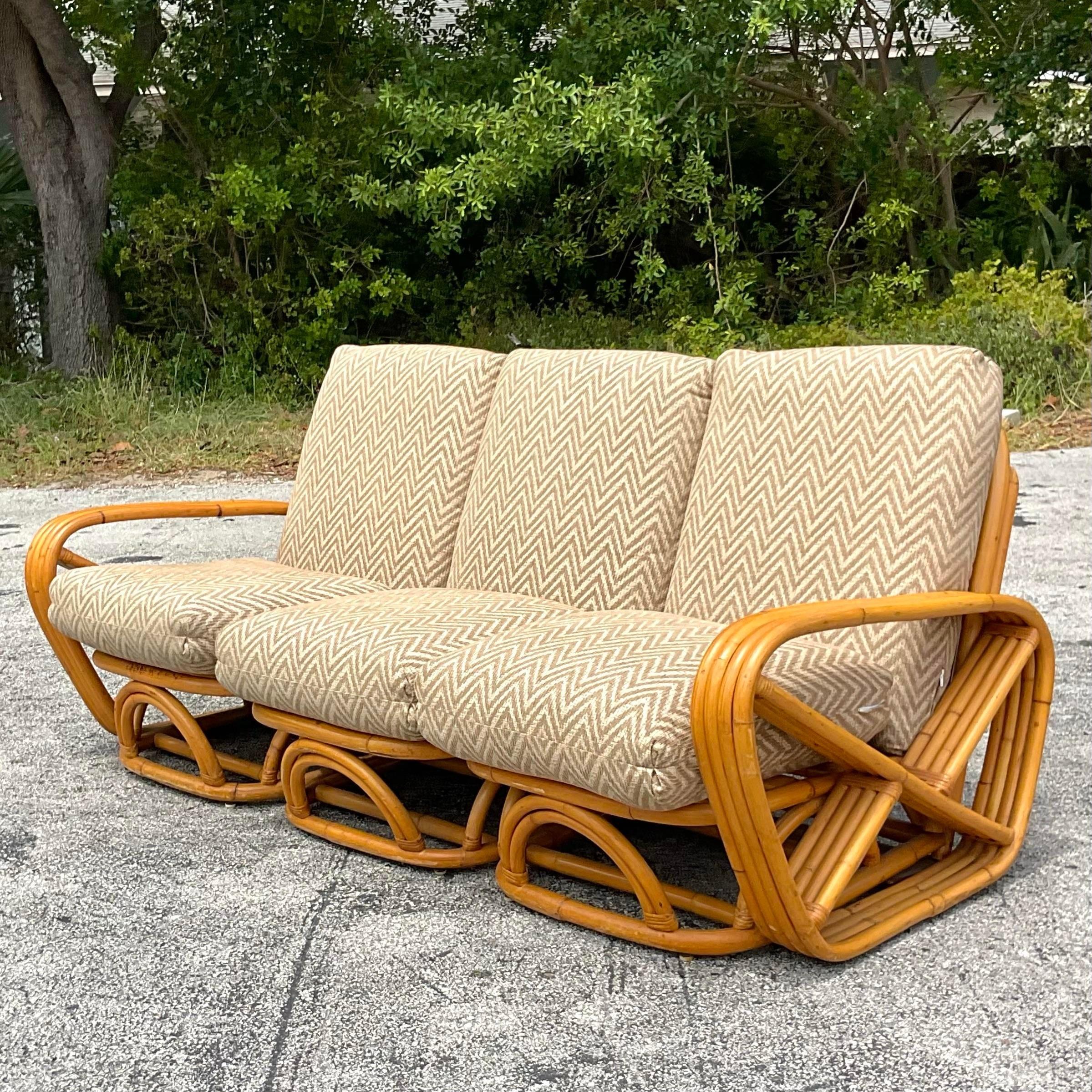 Embrace coastal sophistication with this Vintage Four Strand Bent Rattan Sofa, reminiscent of iconic designs by Frankl. Crafted with American flair, its elegant four-strand construction and natural rattan weave offer a timeless blend of comfort and