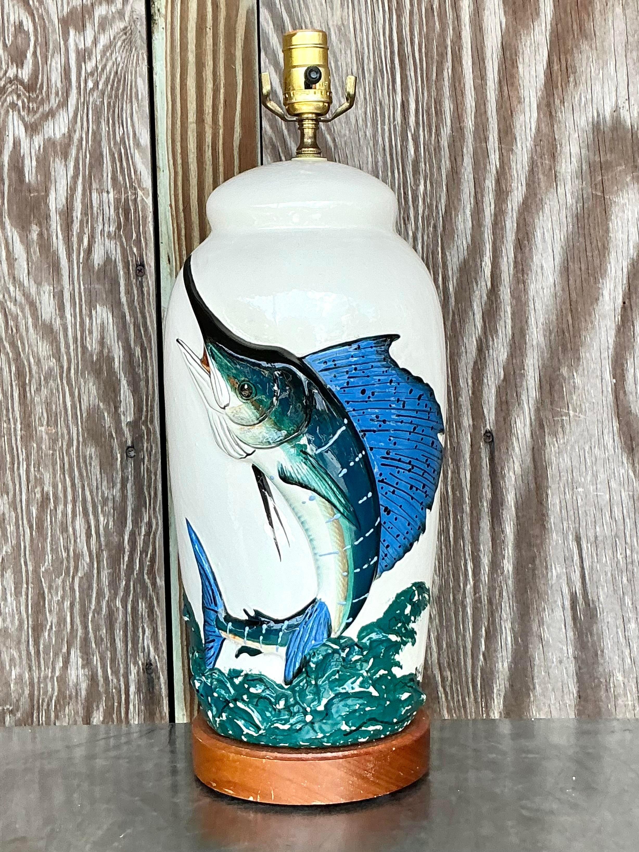 Une superbe lampe vintage en céramique émaillée représentant un voilier de pêche côtière, capturant l'élégance dynamique de la mer. Le design du poisson-voile est audacieux, avec une finition riche et brillante qui lui donne une profondeur qui
