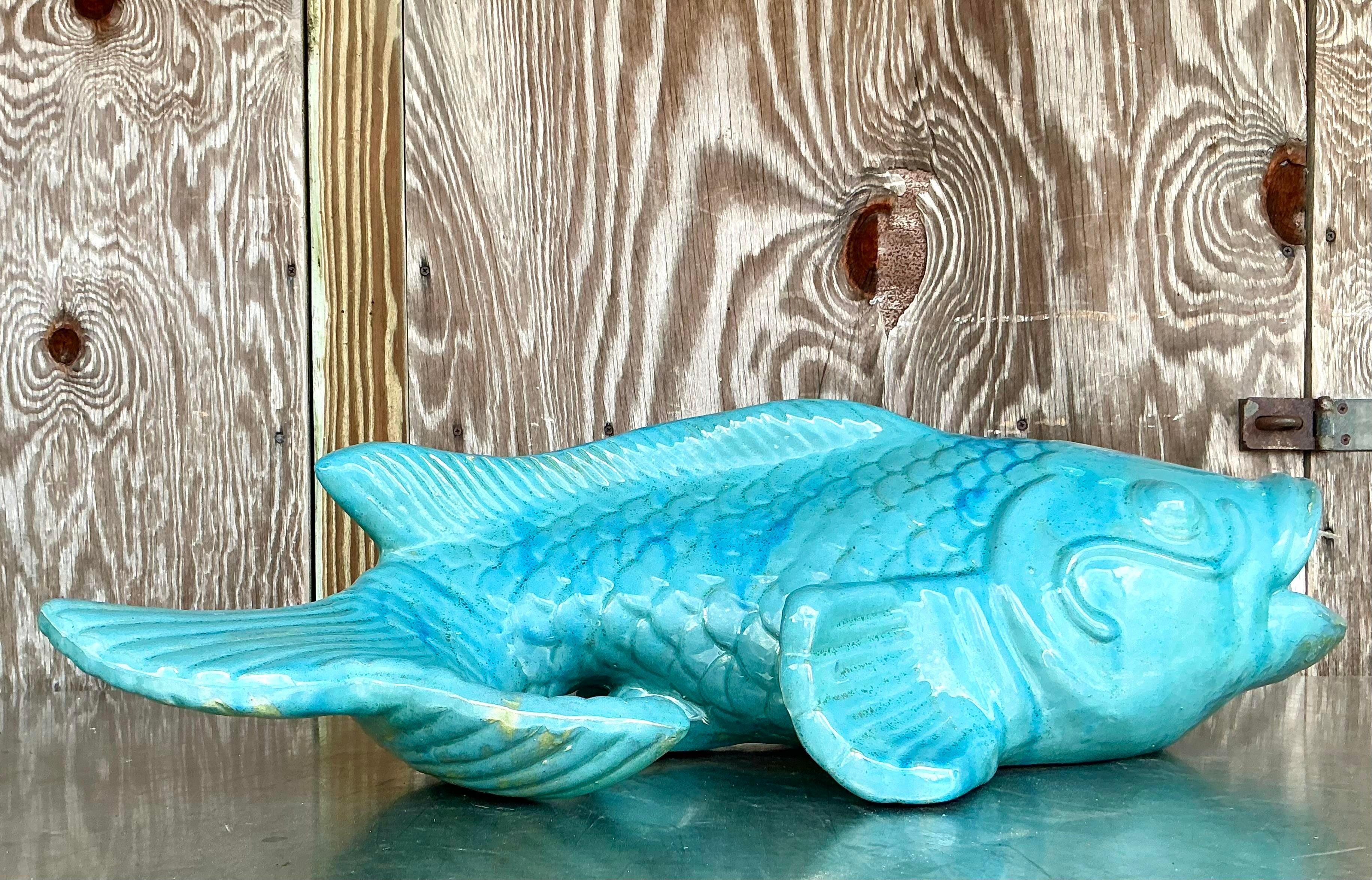 Bring coastal charm to your home with this Vintage Coastal Glazed White Terracotta Fish. Handcrafted from terracotta, this whimsical piece showcases intricate detailing, capturing the essence of oceanic life in a smooth, white-glazed finish. Its
