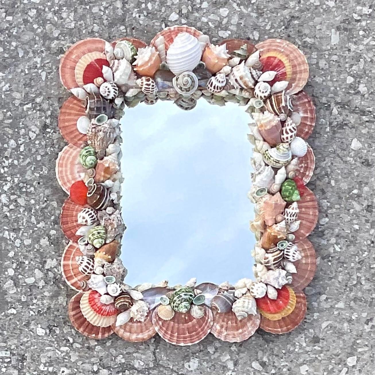 A fantastic vintage Coastal wall mirror. A chic hand made collection of shells in brilliant rosy hues. Acquired from a Palm Beach estate. 