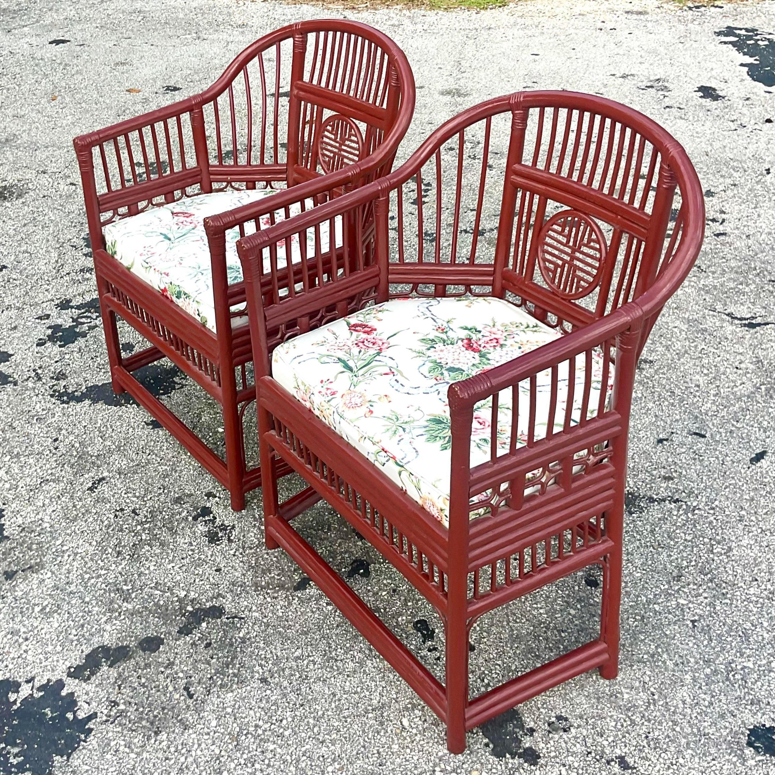 A fabulous pair of vintage Coastal lounge chairs. The classic Brighton Pavilion shape in a wine colored matte lacquered finish. Beautiful floating floral cushions over a rattan seat. Acquired from a Palm Beach estate.