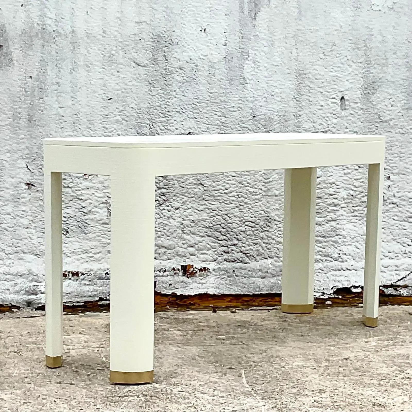 Stunning vintage Century Furniture console table. Beautiful linen wrapped contemporary shape. Brass end cap feet. Freshly painting in a Parzinger white. Chic and sophisticated. Acquired from a Palm Beach estate.