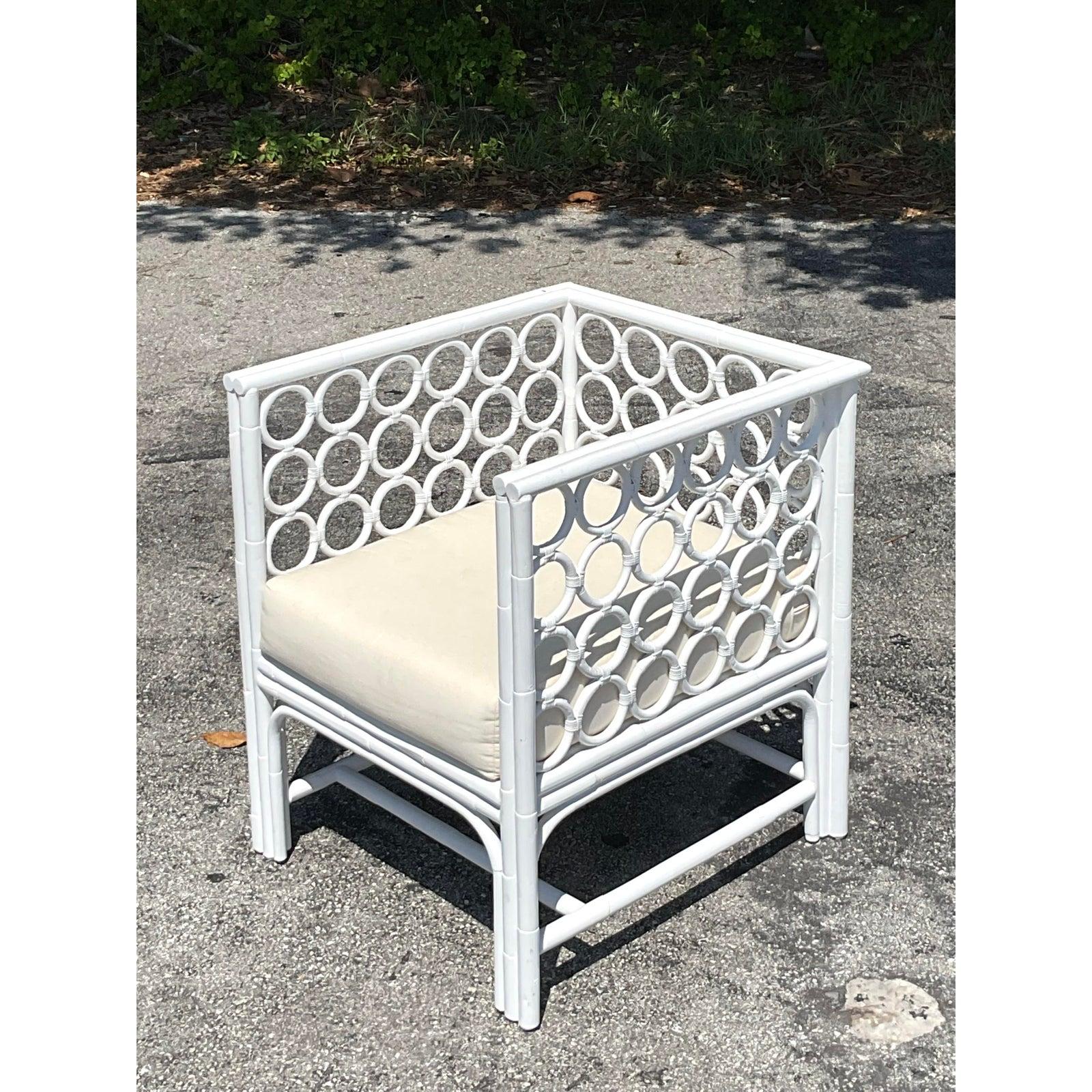 Dieser bezaubernde Rattan-Loungesessel mit Looping im Vintage-Stil steht für entspannte Eleganz an der Küste. Das Gestell des Stuhls ist in frischem Weiß lackiert und weist an den Armlehnen und Seitenteilen ein auffälliges Rattangeflecht in Form von