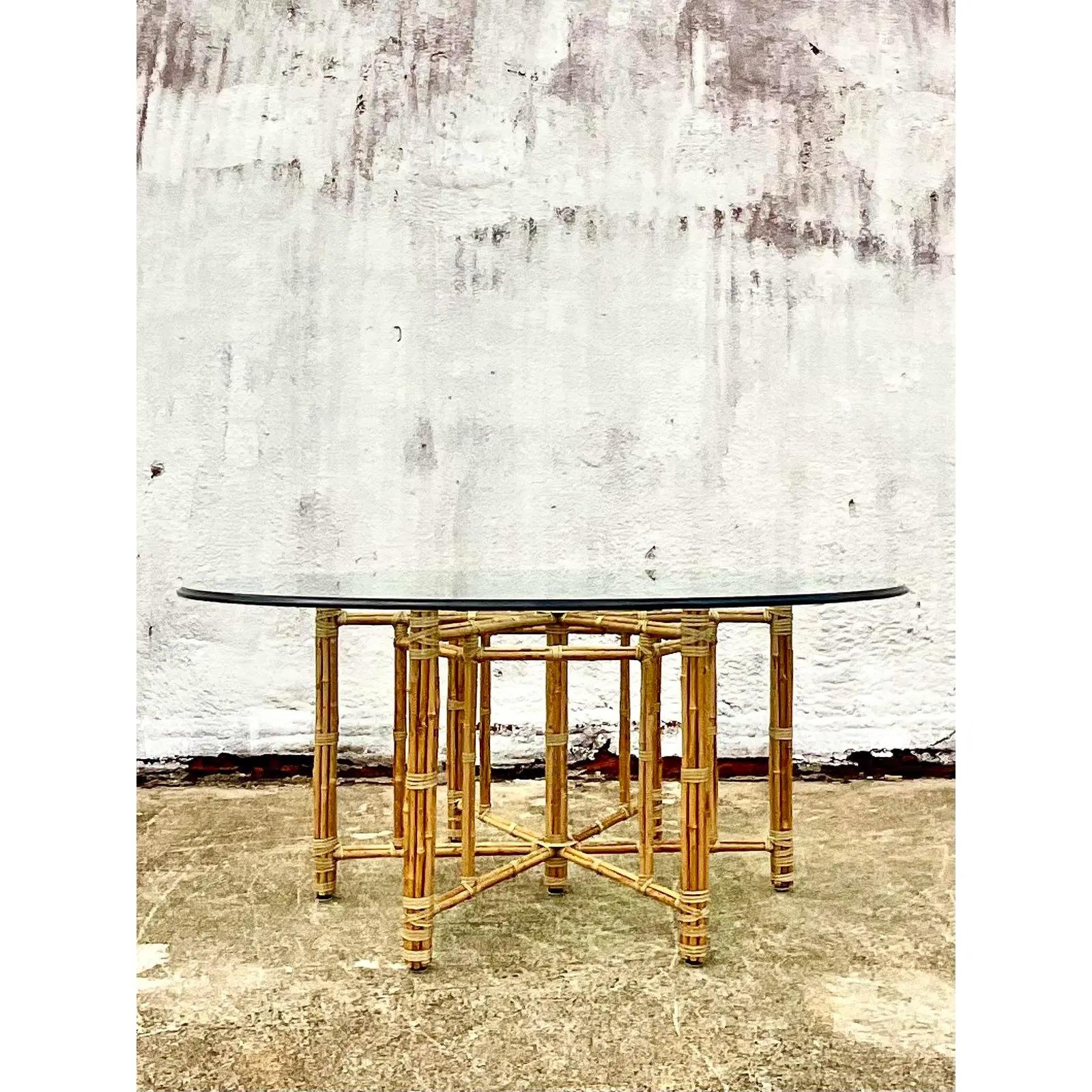 Fantastic vintage McGuire dining table. Steel frame wrapped in bamboo and bundled together with rawhide strips. A real work of art. Thick glass with a beveled edge. Acquired from a Palm Beach estate.