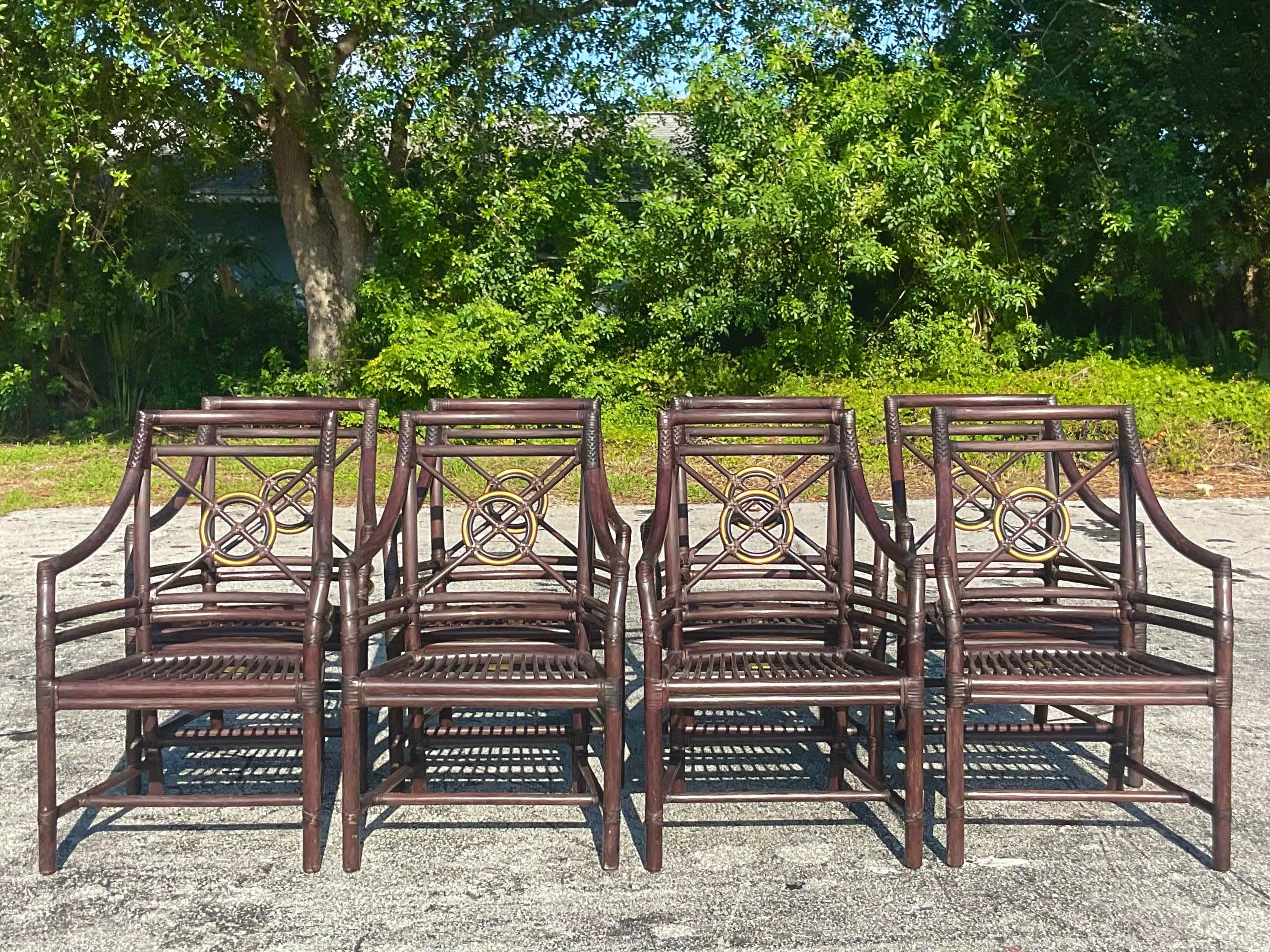 A spectacular set of vintage Coastal dining chairs. Made by the iconic McGuire group and tagged on the bottom. Chic bent rattan in a matte chocolate brown finish. The coveted target back design in a gilt tipped circle. Acquired from a Palm Beach