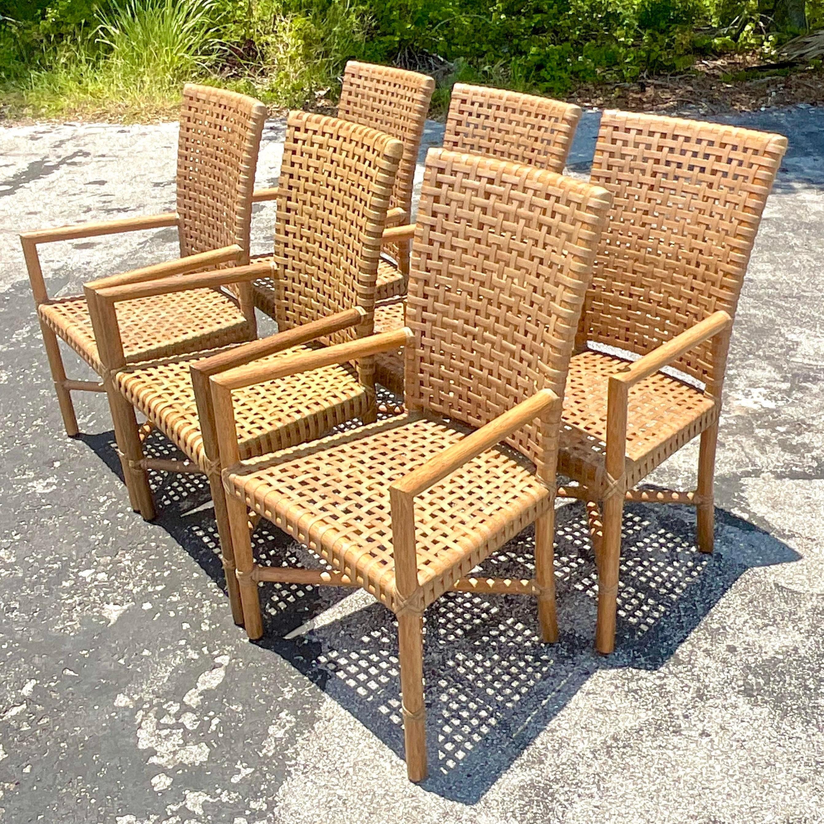 An extraordinary set of six vintage Coastal dining chairs. Made by the iconic McGuire group. Six stylish arm chairs with chic woven rawhide seats. Tagged on the bottom. Acquired from a Palm Beach estate.