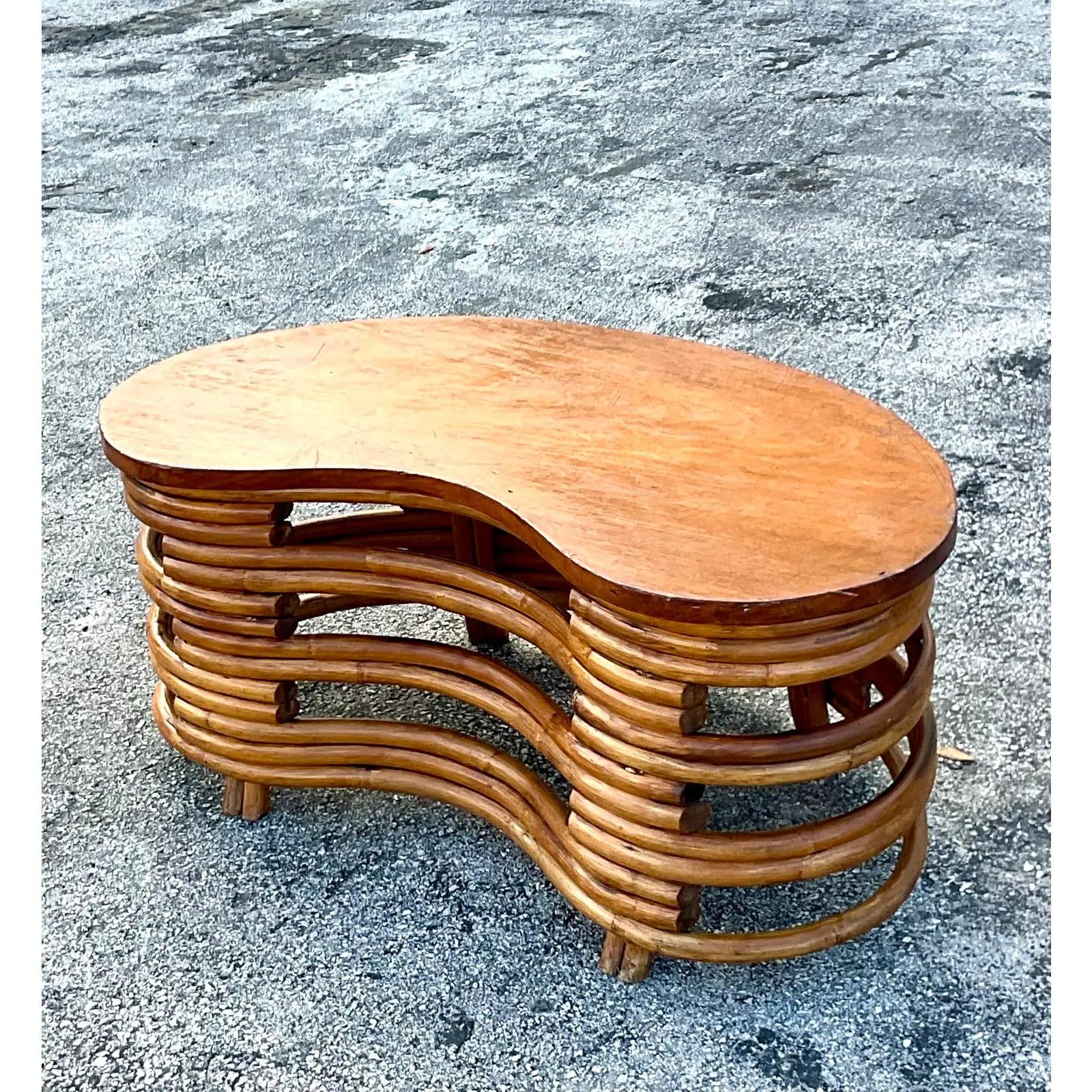 Fantastic vintage MCM Rattan coffee table. Done in the manner of the iconic Paul Frankl. A chic kidney bean shape with a solid wood top. Acquired from a Palm Beach estate.