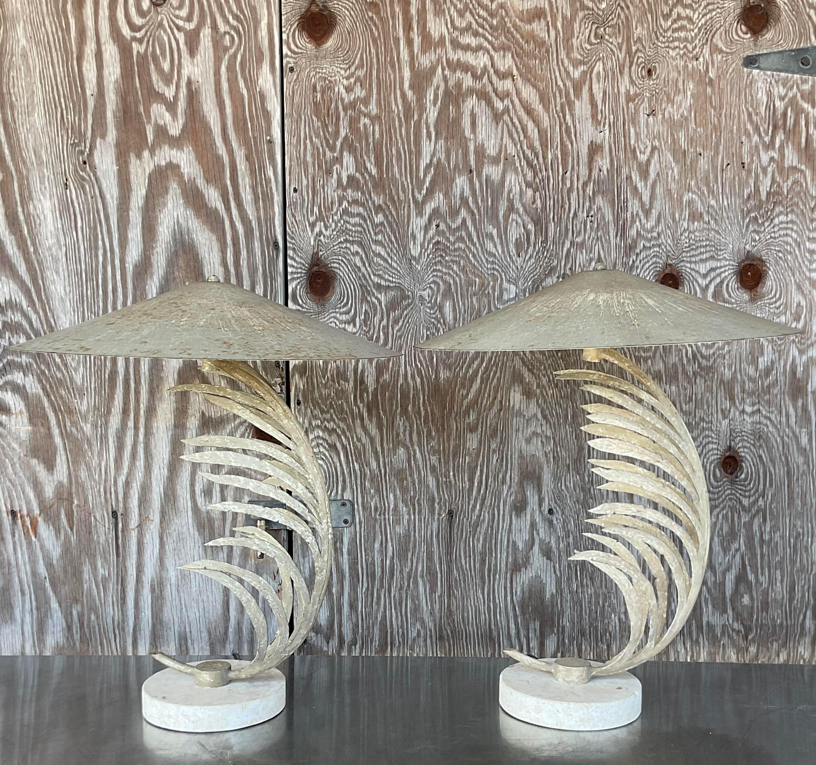 An exceptional pair of vintage Coastal table lamps. The iconic Frond design by Michael Taylor. Beautiful metal fronds that rest on a travertine plinth. Coordinating metal shades. Acquired from a Palm Beach estate.