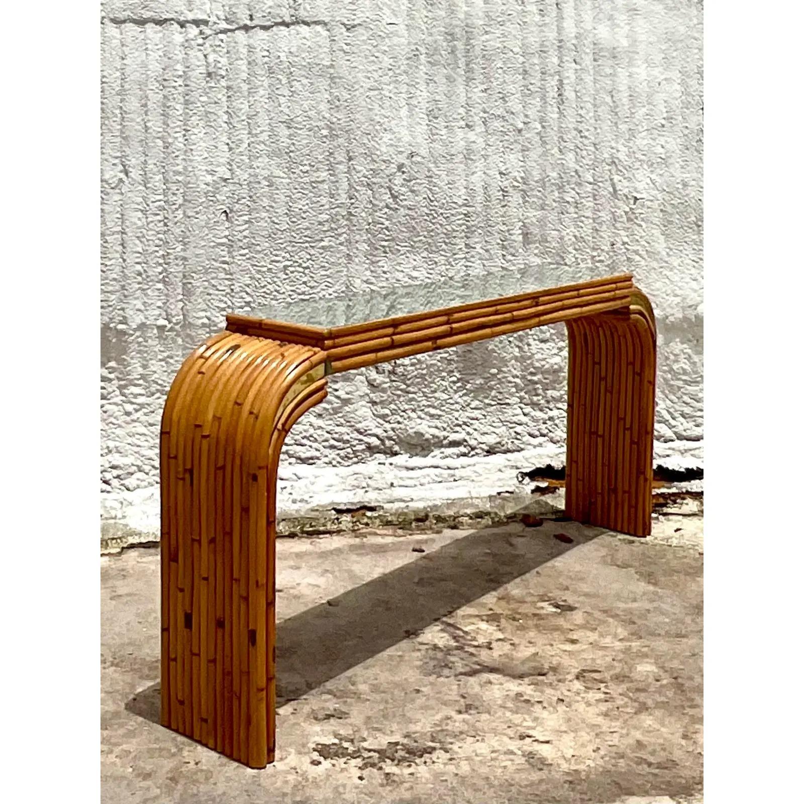 Fabulous vintage bamboo console table. Beautiful waterfall shape with brass detail inset panels. Matching mirror also available. Acquired from a Palm Beach estate.