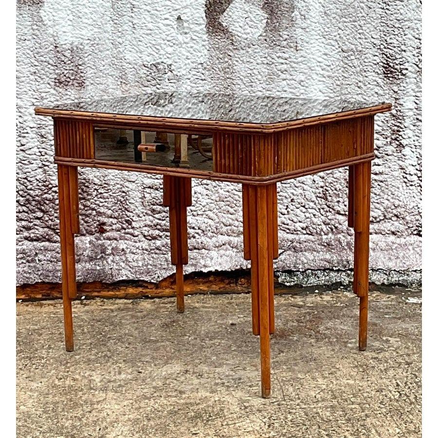 Porta l'eleganza costiera nel tuo spazio di lavoro con questo scrittoio vintage in rattan specchiato. Caratterizzata da una splendida struttura in rattan intrecciato e da un piano riflettente a specchio, questa scrivania unisce la consistenza