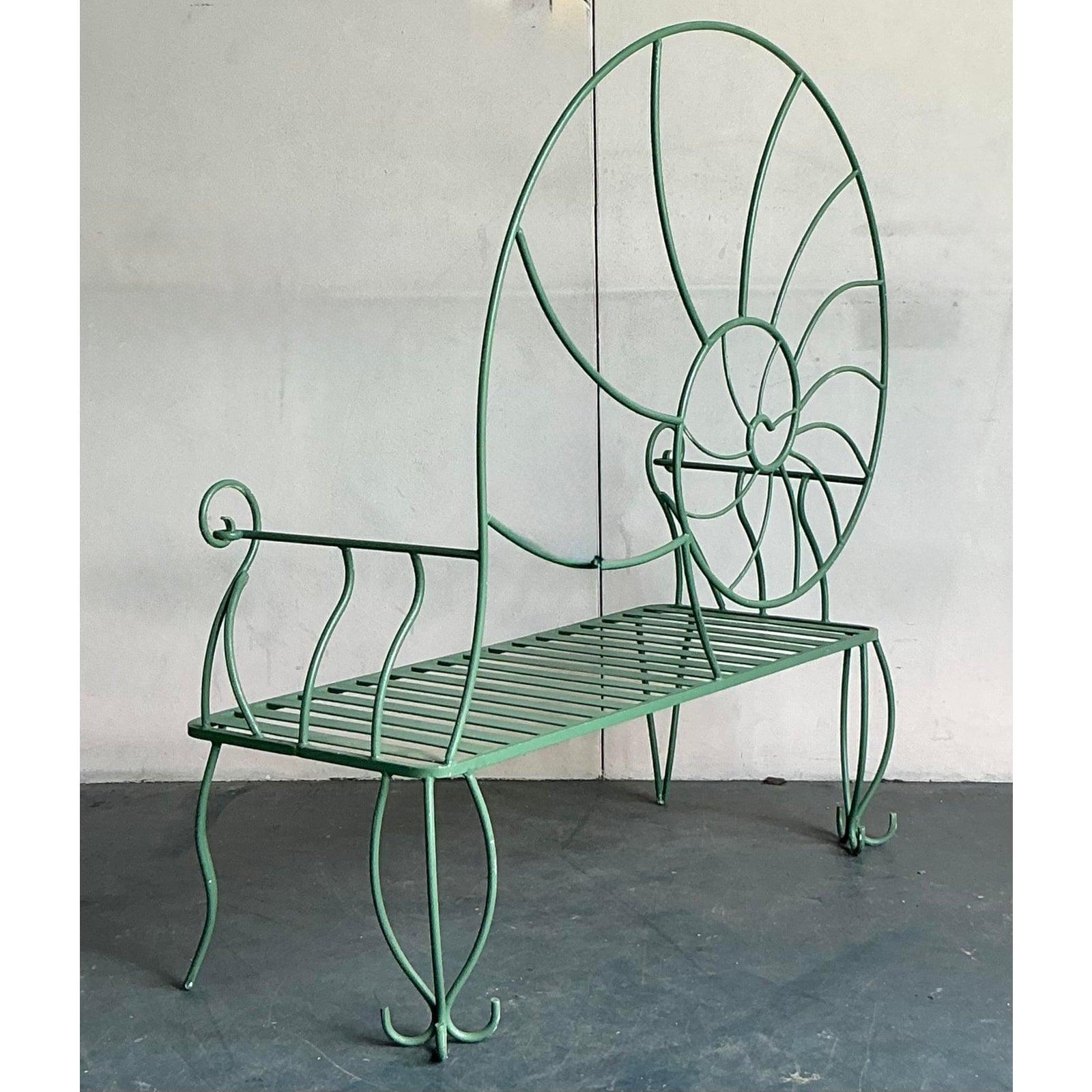This exquisite vintage wrought iron bench, designed in the majestic form of a nautilus shell, offers a striking blend of artistry and functionality. Its monumental scale and intricate scrollwork evoke a sense of coastal elegance and timeless charm,