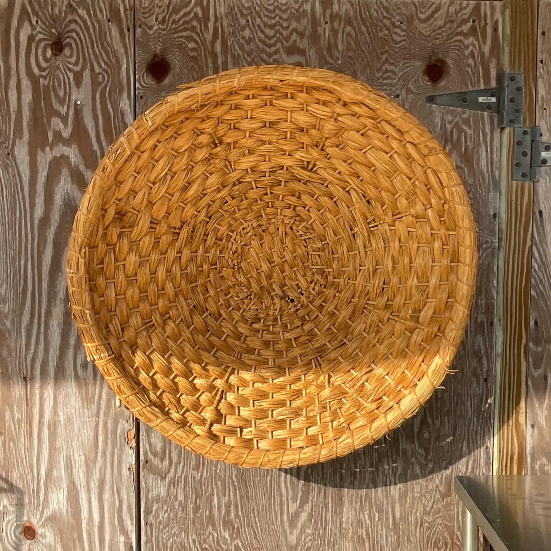 A vintage Coastal woven rattan wall plate. A large decorative disc that will add lots of tropical texture to your space. Acquired from a Palm Beach estate. 