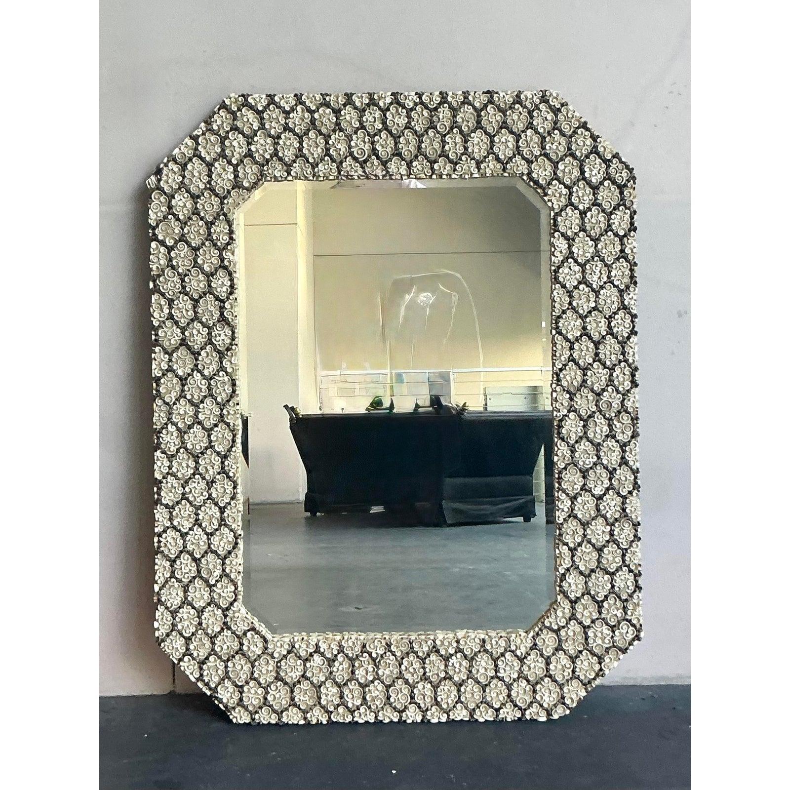 Lassen Sie sich von der Kunstfertigkeit der Küste inspirieren - mit diesem atemberaubenden Muschelspiegel im Vintage-Stil. Der massive Rahmen ist ein Meisterwerk der Handwerkskunst, das mit einem dichten Mosaik aus cremeweißen Muschelspiralen