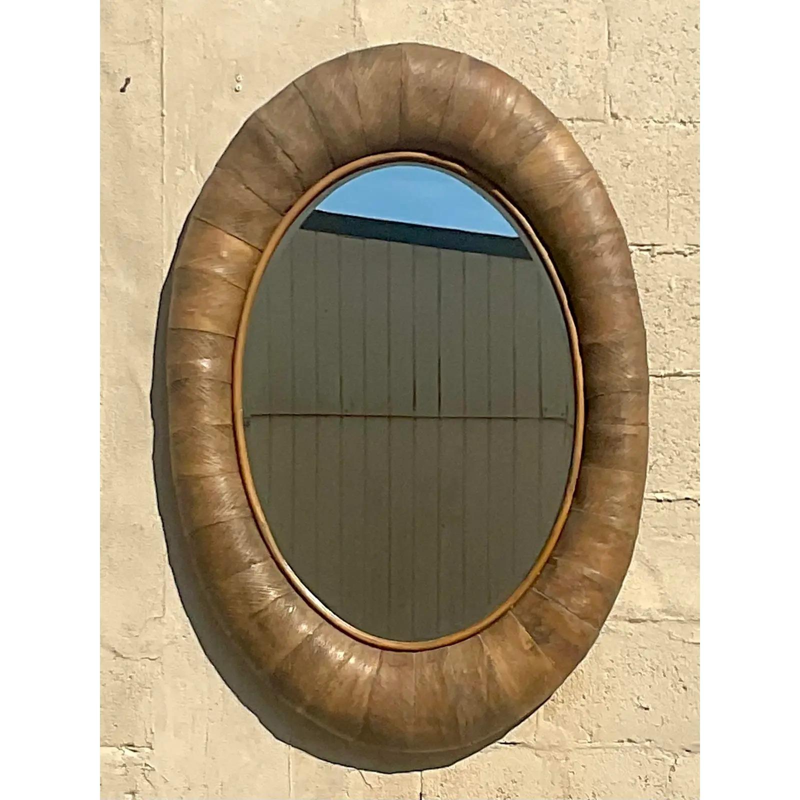 A chic and fantastic oval wall mirror. Beautiful wrapped coconut husk frame. Acquired from a Palm Beach estate.