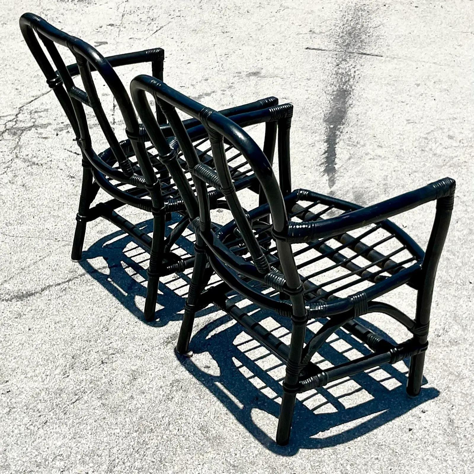 A fabulous pair of vintage rattan arm chairs. Deep seats and a clean and simple design. A chic semigloss black finish. Acquired from a Palm Beach estate.