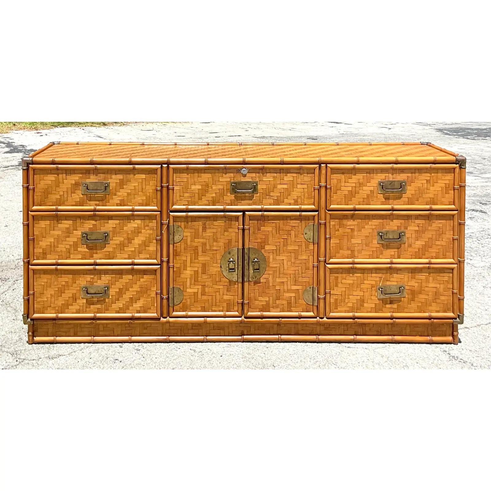 Fantastic vintage Coastal credenza. Beautiful parquet rattan frame with carved bamboo trim. Heavy brass hardware with a medallion plaque in the center. Acquired from a Palm Beach estate.