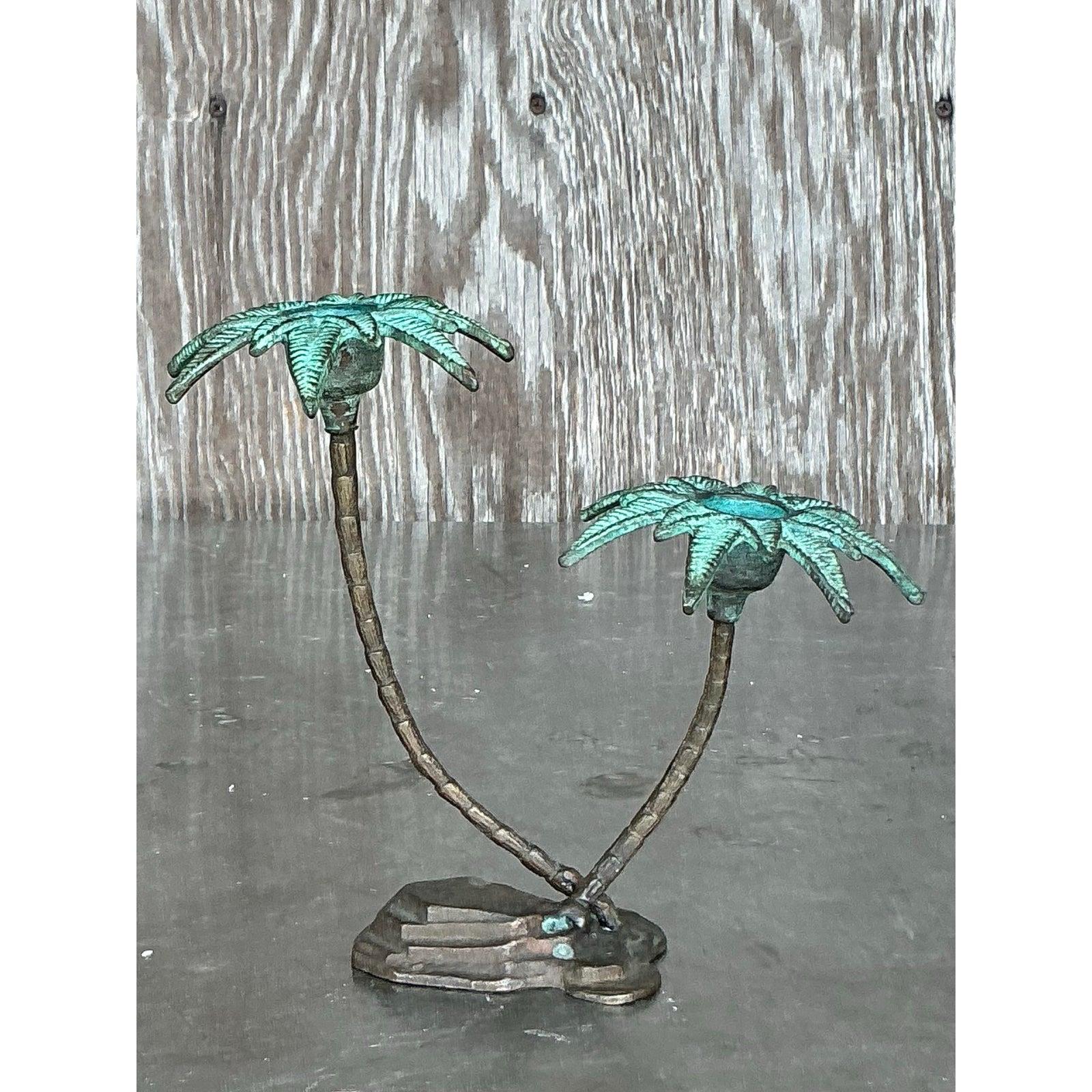 Trasporta il tuo spazio in una ventilata fuga costiera con questa affascinante coppia di candelabri a forma di palma in metallo patinato vintage. Realizzati meticolosamente con una finitura verdognola, questi portacandele doppi donano un tocco