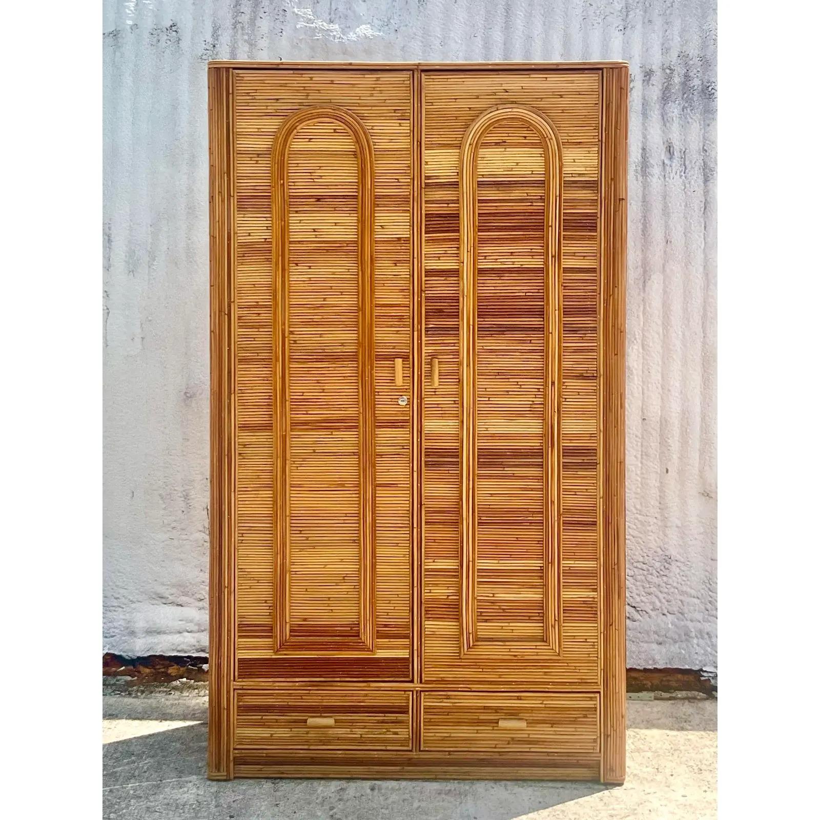 A fantastic vintage Coastal armoire. Stunning pencil reed cabinet with a chic arched design. Lots of great storage and and area for hanging. Currently keyed in front with an additional locking interior drawer. Keys included. Perfect for locking up