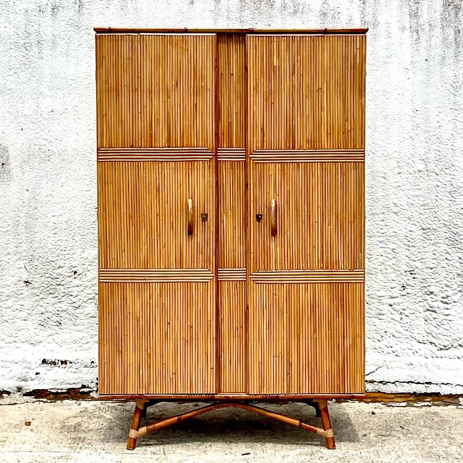 Fantastic vintage Coastal armoire. Incredible pencil reed cabinet with bent rattan base. Lots of great interior storage with shelving in one side and a front to back hang bar on the other side. Would be sensational if mirrored on the inside and