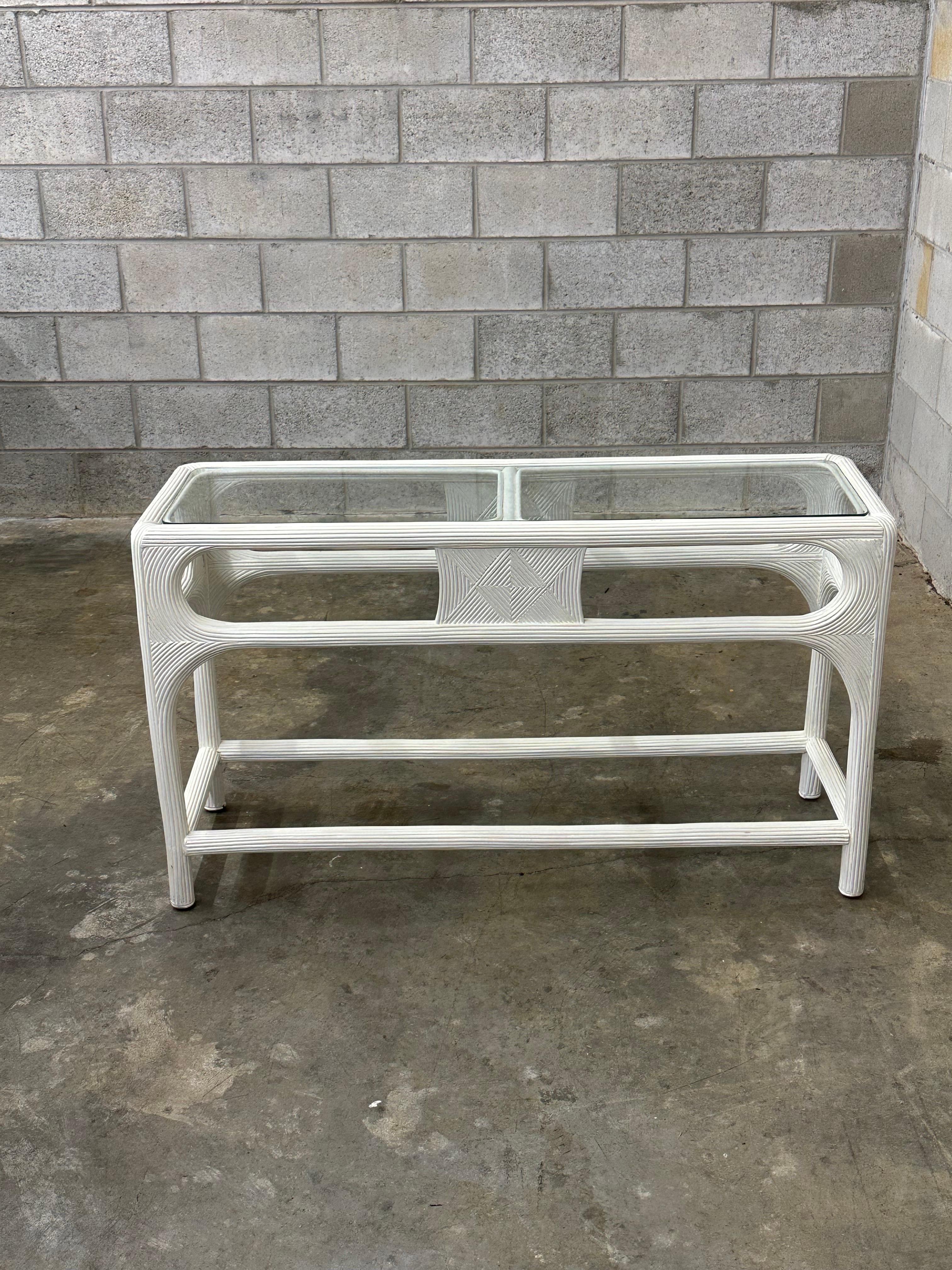 Gorgeous pencil reed console table in white. Has a very unique design with great movement. Much more intricate than others more commonly seen. Glass top helps complete this wonderful coastal styled console. 
