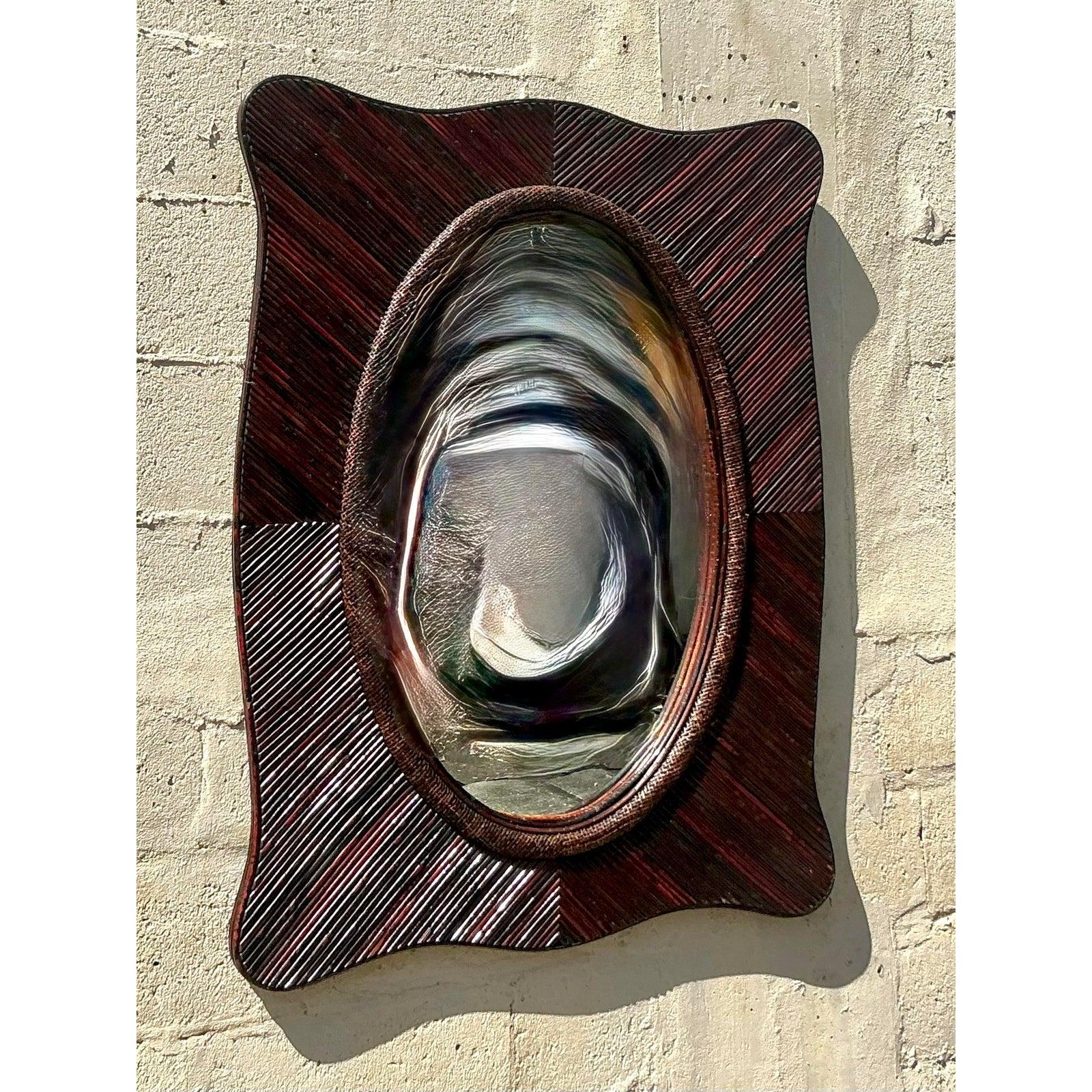 This striking vintage pencil reed mirror captures the essence of coastal charm with a bold, sculptural frame and beautifully textured detailing. The hand-wrapped rattan design forms a dynamic wave-like silhouette around an oval inset mirror, making