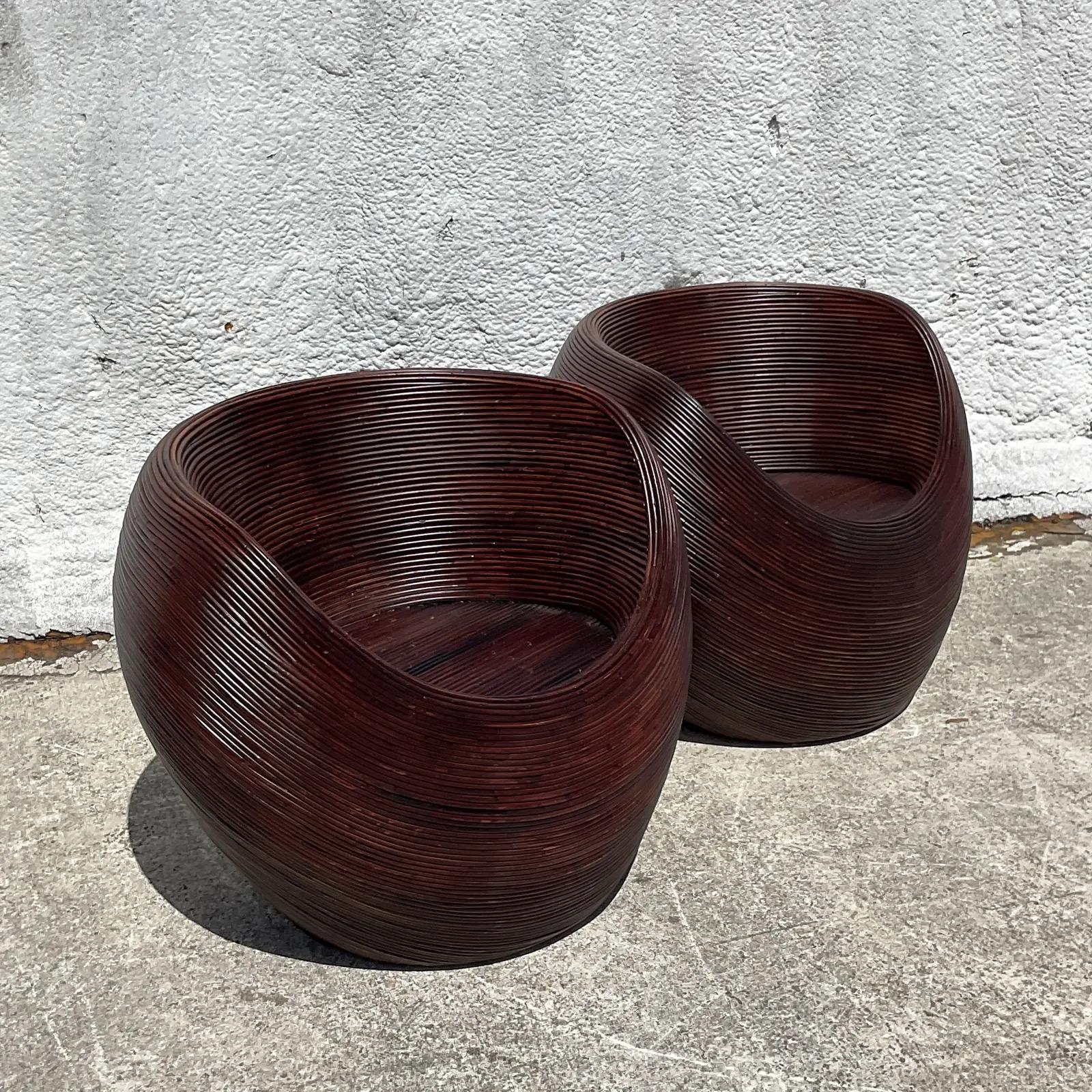 Fabulous pair of vintage Coastal lounge chairs. The iconic pod chair design made in coiled pencil reed. A rich brown color with a gloss finish. Acquired from a Palm Beach estate.