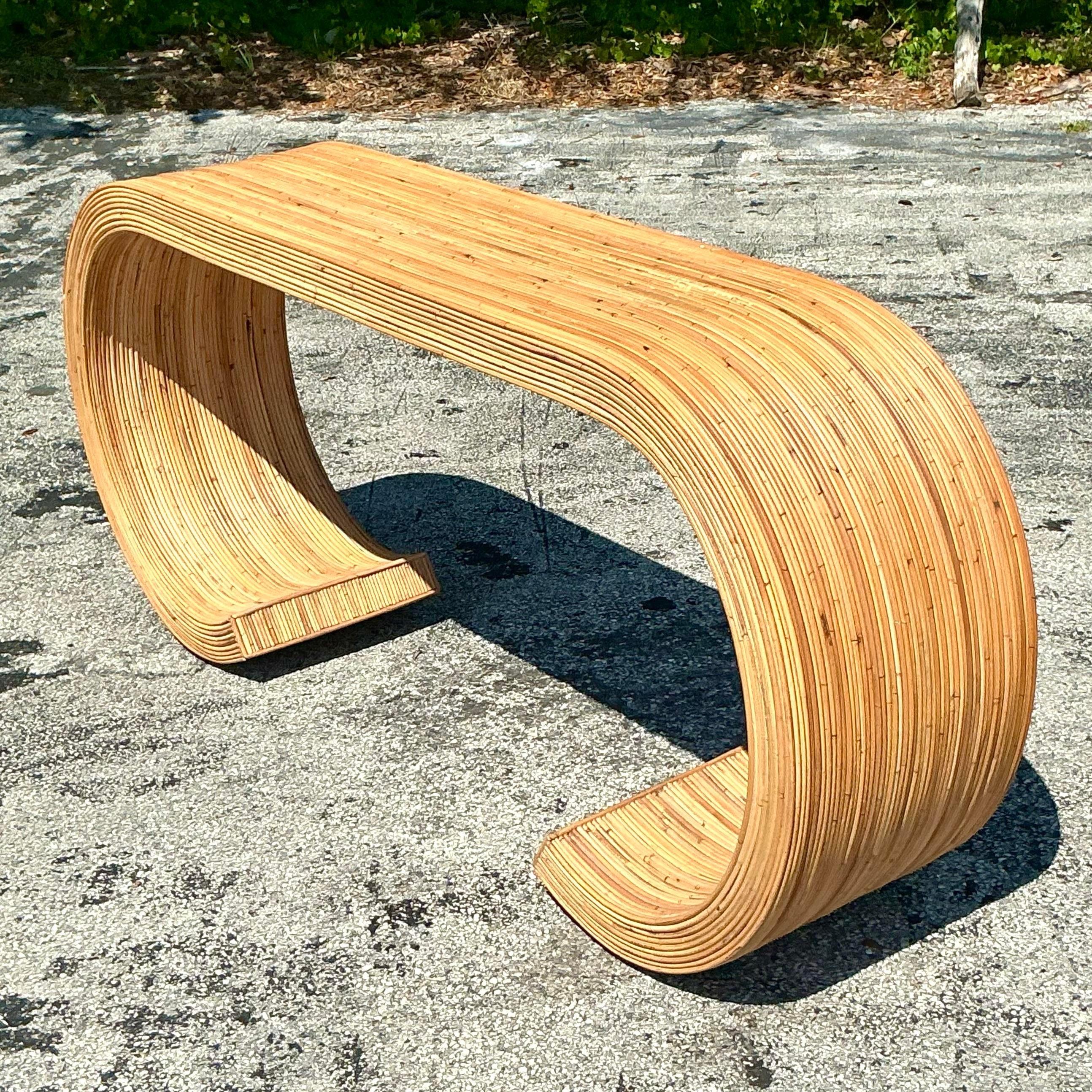 Vintage coastal pencil reed console table with elegant scroll design. A stylish blend of natural texture and coastal charm. Acquired from a Palm Beach estate.