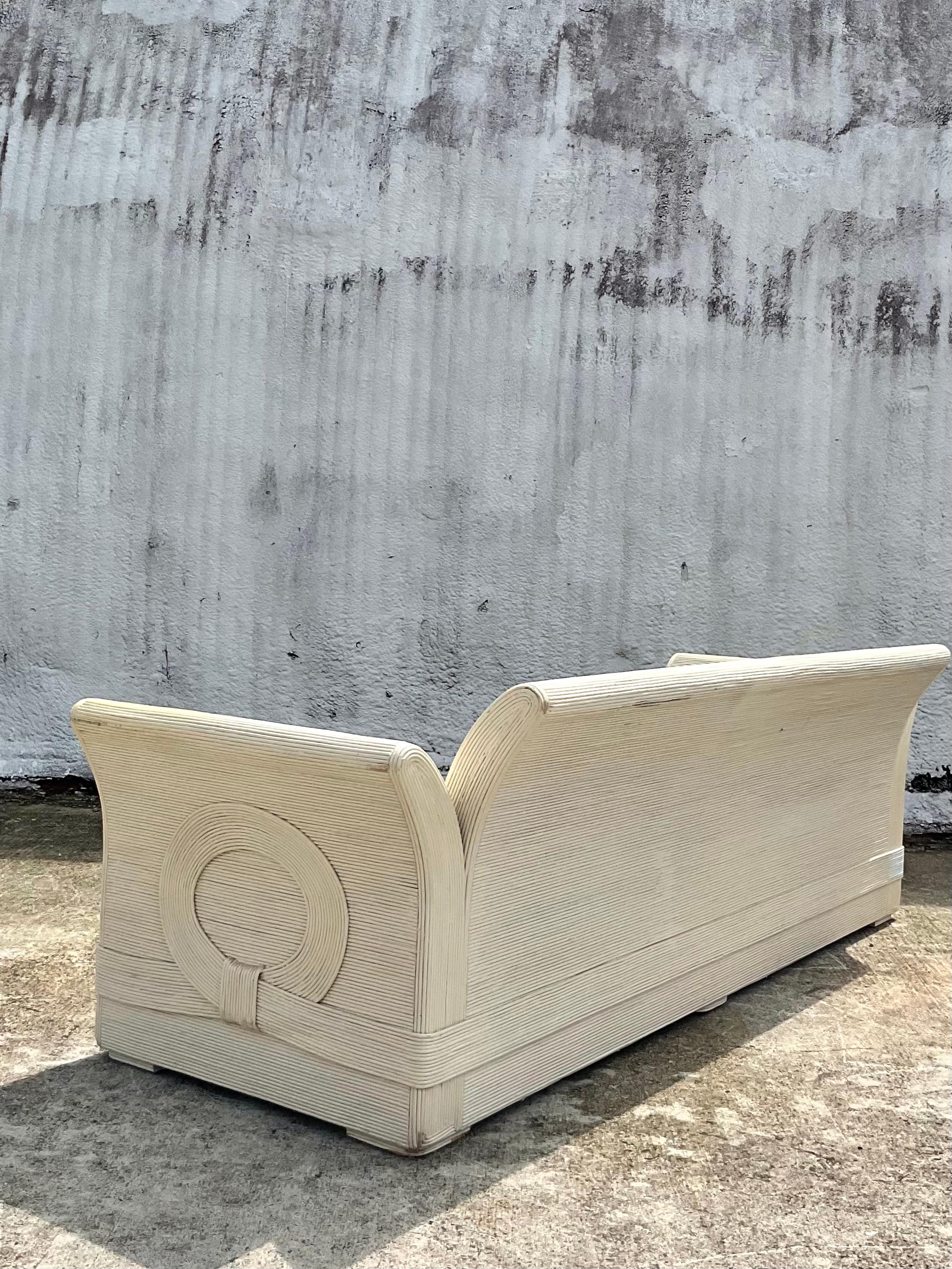 Incredible vintage Coastal sofa. Made from a fabulous painted ribbon pencil reed. Done in the manner of the iconic Betty Cobonpue. A strong and simple frame design with the seductive ribbon of reed that floats around the perimeter of the sofa.