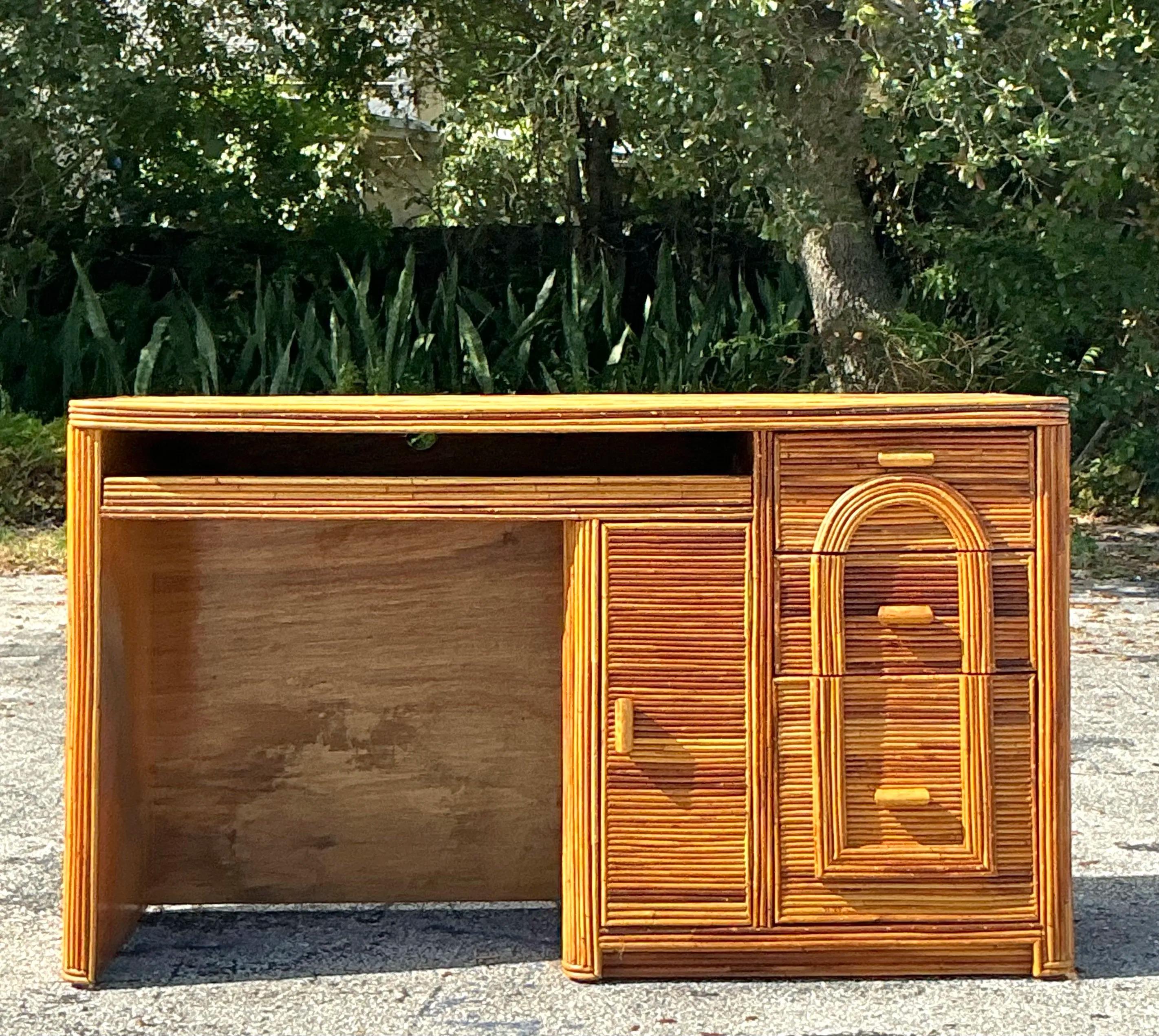 Verschönern Sie Ihren Arbeitsplatz mit diesem Vintage-Schreibtisch aus Schilfrohr im Küstenstil. Sie wurde mit viel Liebe zum Detail gefertigt und zeichnet sich durch ein strukturiertes Bleistiftschilf-Finish und eine schlanke Silhouette aus, die
