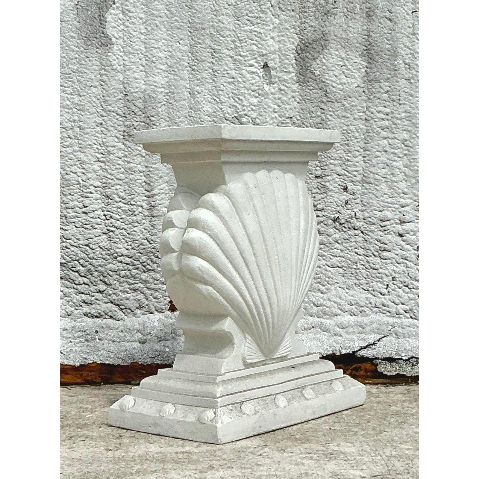 Lleva el encanto del diseño costero a tu casa con esta llamativa consola vintage con pedestal de escayola. Con un motivo de concha de almeja de gran tamaño, esta pieza escultural captura la esencia de la elegancia inspirada en el océano con su
