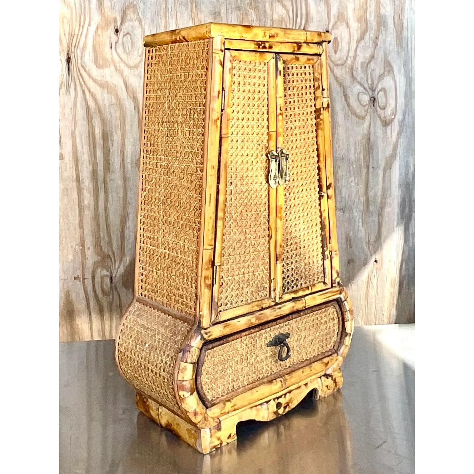 A charming little vintage Coastal cabinet. A chic keyhole shape in bamboo and cane. Perfect on your tabletop, desk or dry bar. Just enough storage for your essentials! Acquired from a Palm a each estate.