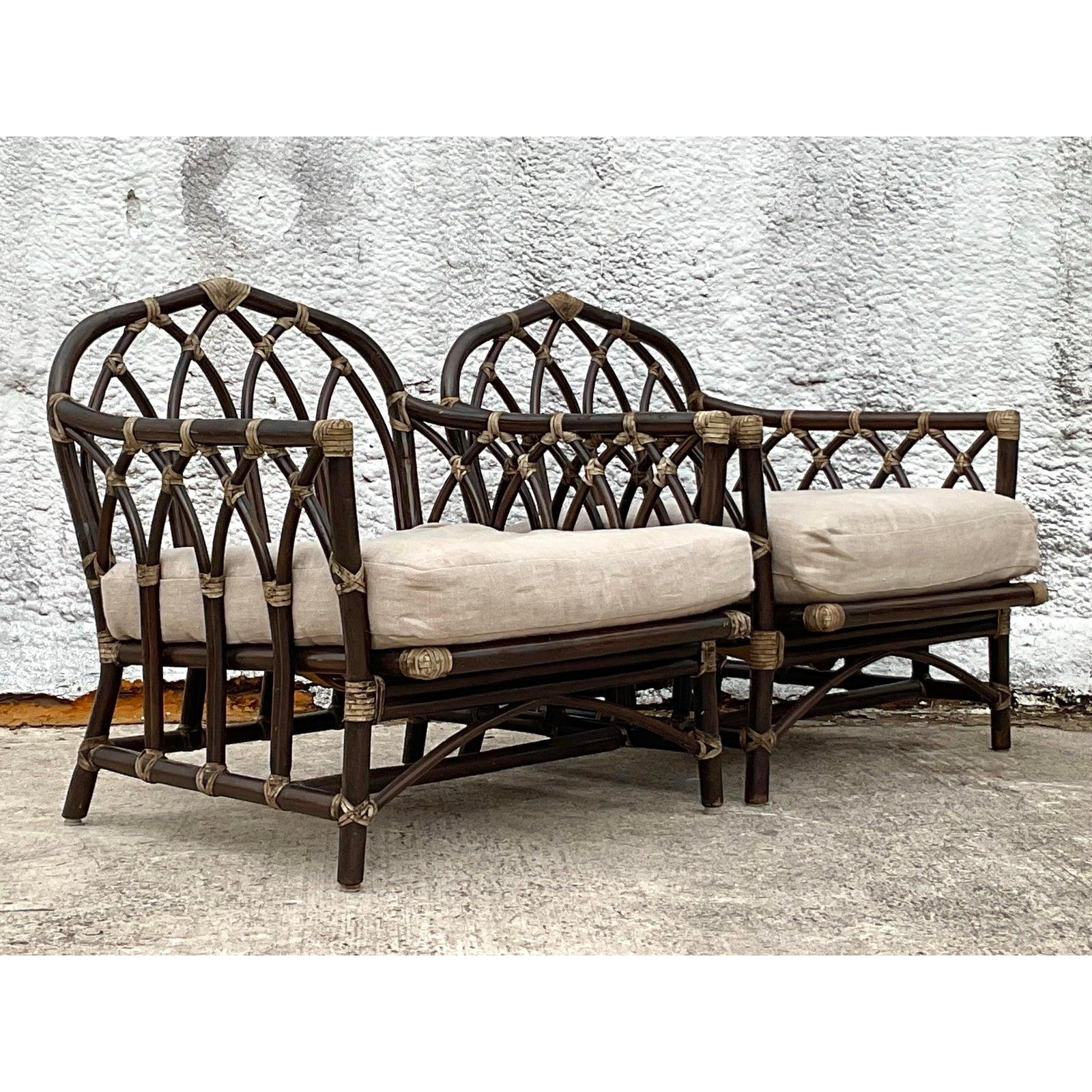 Dieses Paar Vintage-Rattan-Loungesessel mit Küstencharme und klassischem, von McGuire inspiriertem Design bietet die perfekte Kombination aus Kunstfertigkeit und Komfort. Mit einer gewölbten Rückenlehne mit Gitterwerk im Kathedralenstil,
