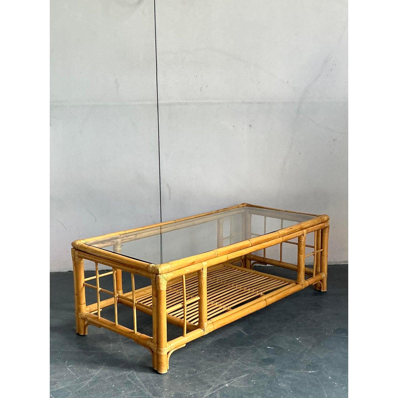Lassen Sie sich von der zeitlosen Anziehungskraft des Küstendesigns anstecken - mit diesem atemberaubenden Vintage-Rattan-Couchtisch. Dieses meisterhaft aus einem robusten Bambusrahmen gefertigte Stück zeigt die organische Wärme und die