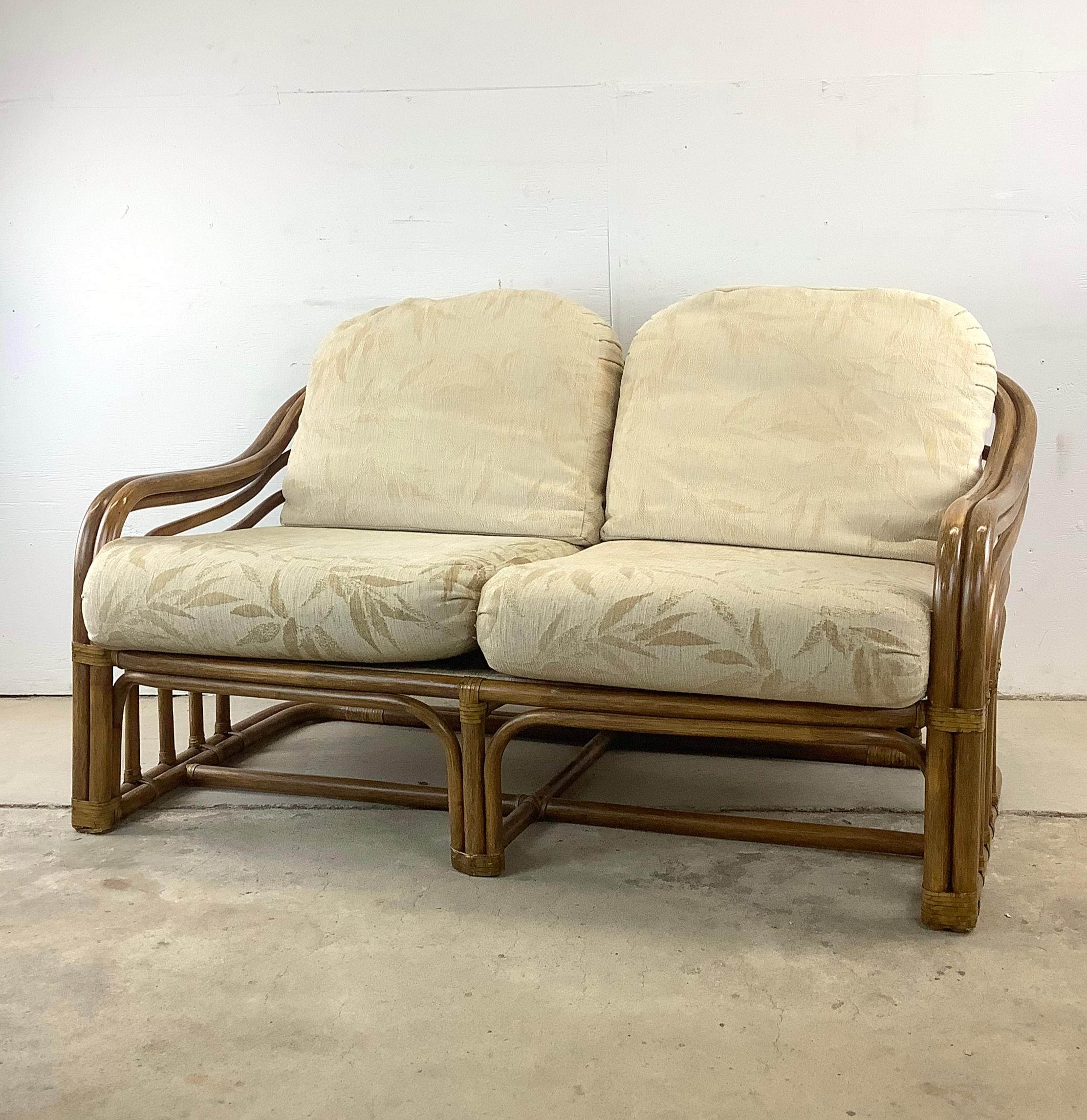Embrace the charm of cozy, intimate seating with this vintage coastal rattan loveseat after Brown Jordan, a piece that perfectly marries comfort with compact elegance. This loveseat, with its inviting bentwood rattan frame and plush upholstery, is
