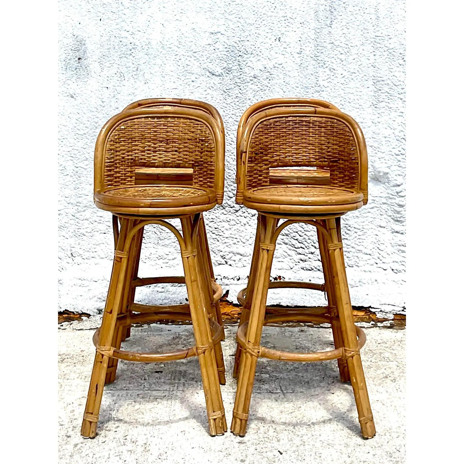 Fantastic set of four vintage Coastal bar stools. Beautiful wrap around swivel seats with inset woven rattan panels. Chic and simple. Acquired from a Palm Beach estate.