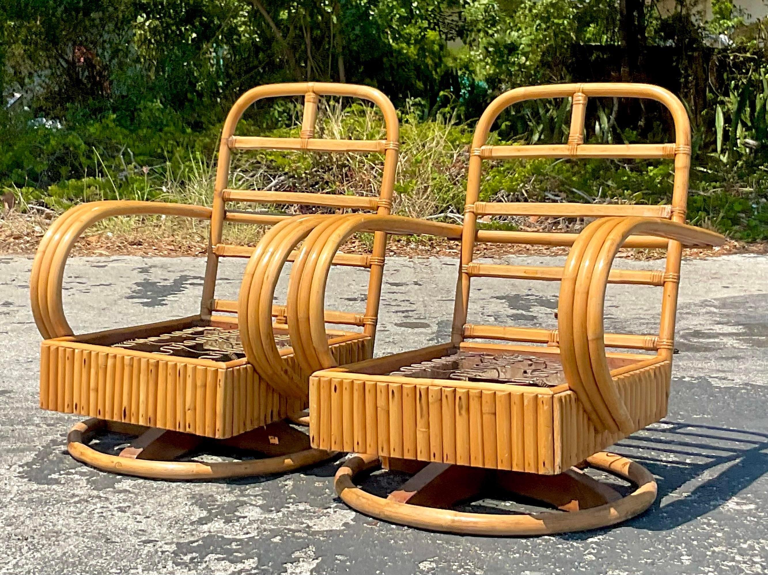 Une fantastique paire de chaises pivotantes Vintage By. De beaux cadres d'époque avec une épaisse bande de rotin. Un profil chic avec la belle patine du temps. Acquis d'une propriété de Palm Beach.
