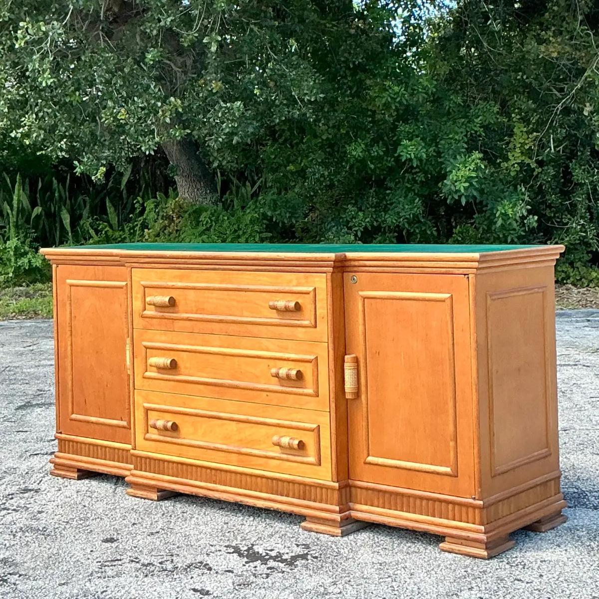 Aggiungi un tocco di raffinatezza costiera al tuo spazio con questa credenza vintage rivestita in rattan. Caratterizzato da linee pulite e texture naturali, questo pezzo è avvolto in un bellissimo rattan intrecciato che offre stile e spazio. I suoi