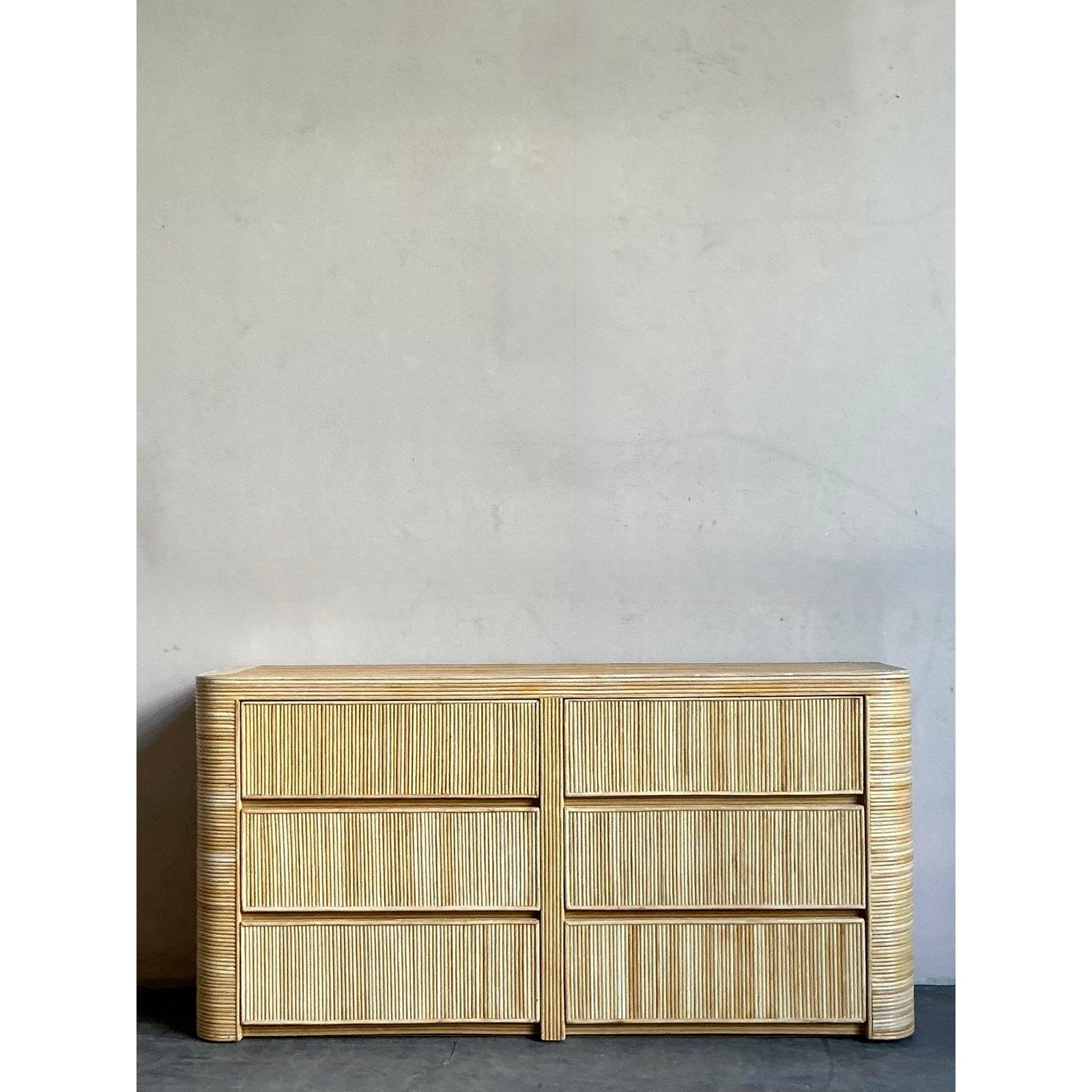 Esempio straordinario di design di fine Novecento, questo comò d'epoca a sei cassetti è un'affermazione di grande impatto materico. L'intero pezzo è magistralmente avvolto in canne naturali, creando un bellissimo motivo lineare che è allo stesso