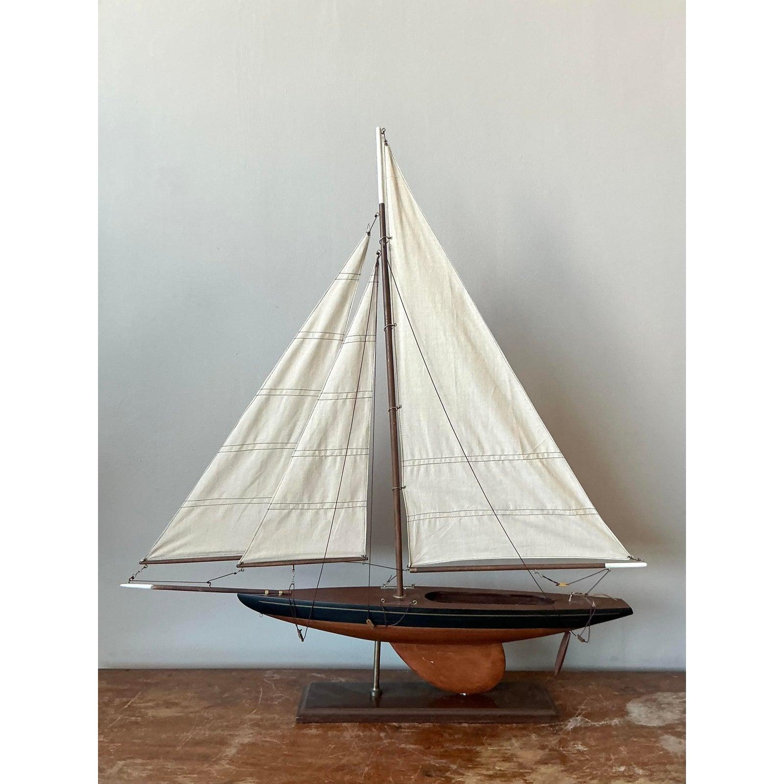 Salpa per uno stile sofisticato con questo affascinante modellino di barca a vela in scala costiera vintage. Questo splendido modello presenta uno scafo in legno scuro, eleganti vele in tela e un delicato sartiame, il tutto meticolosamente