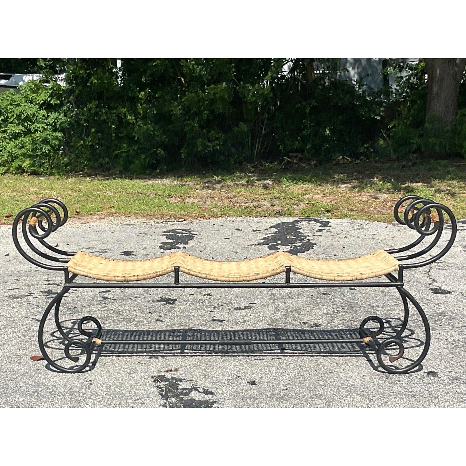 A fabulous vintage Coastal bench. A chic black metal frame with a scalloped design and a woven rattan seat. A real statement piece. Acquired from a Palm Beach estate.