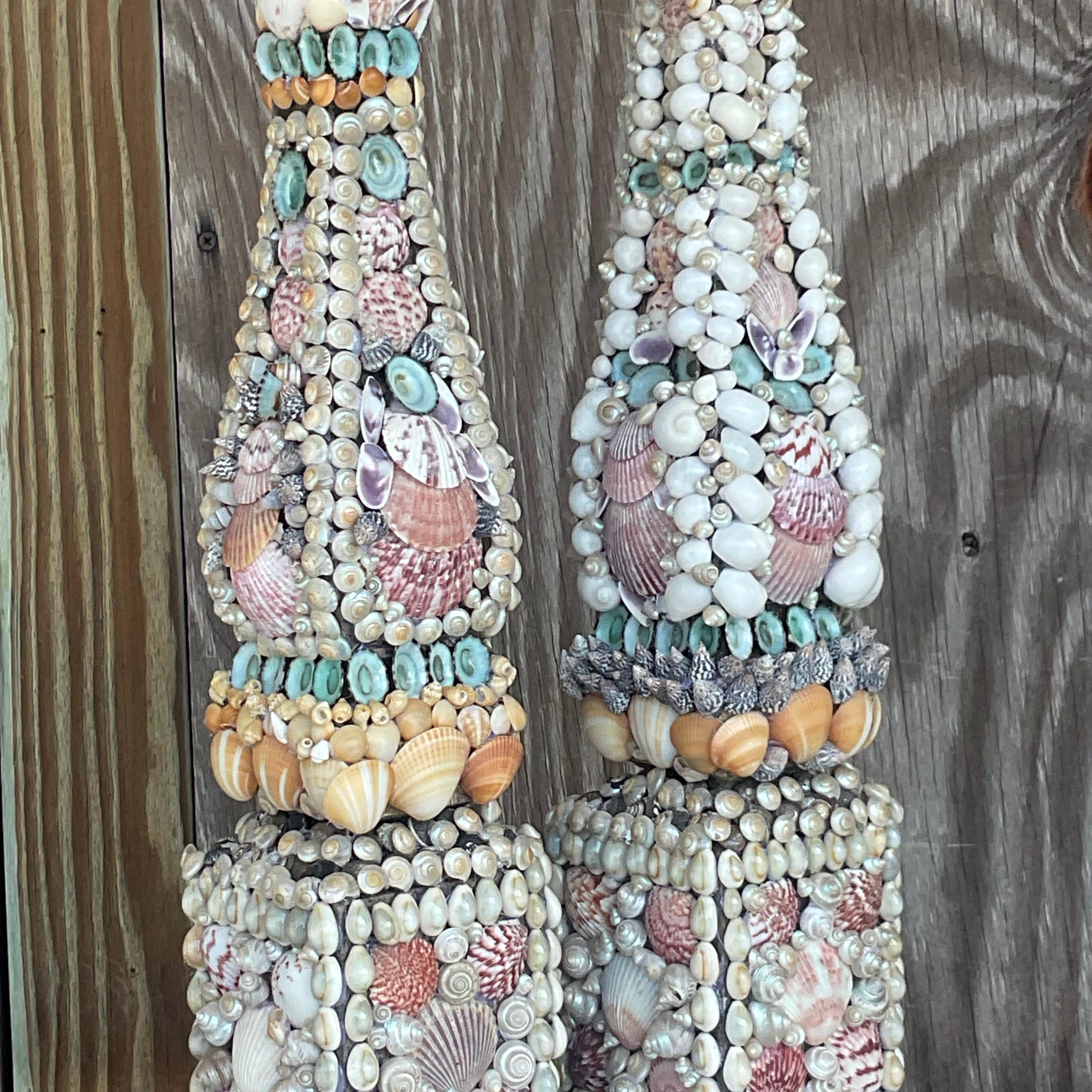 Peppen Sie Ihre Küstendekoration mit unseren Vintage Coastal Shell Encrusted Obelisks auf - ein Set aus zwei exquisiten Stücken, inspiriert von der rauen Schönheit der amerikanischen Küsten. Jeder Obelisk ist sorgfältig mit verkrusteten Muscheln